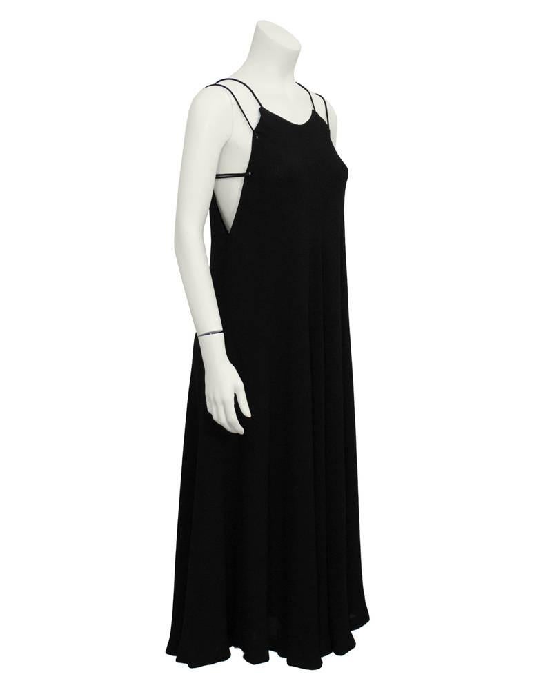 A simple and sleek black Halston gown that dates from the 1970's. High neck with two spaghetti laced straps that tie at the back. Loose-fitting swing cut. A go-to piece for any special event. Excellent vintage condition.