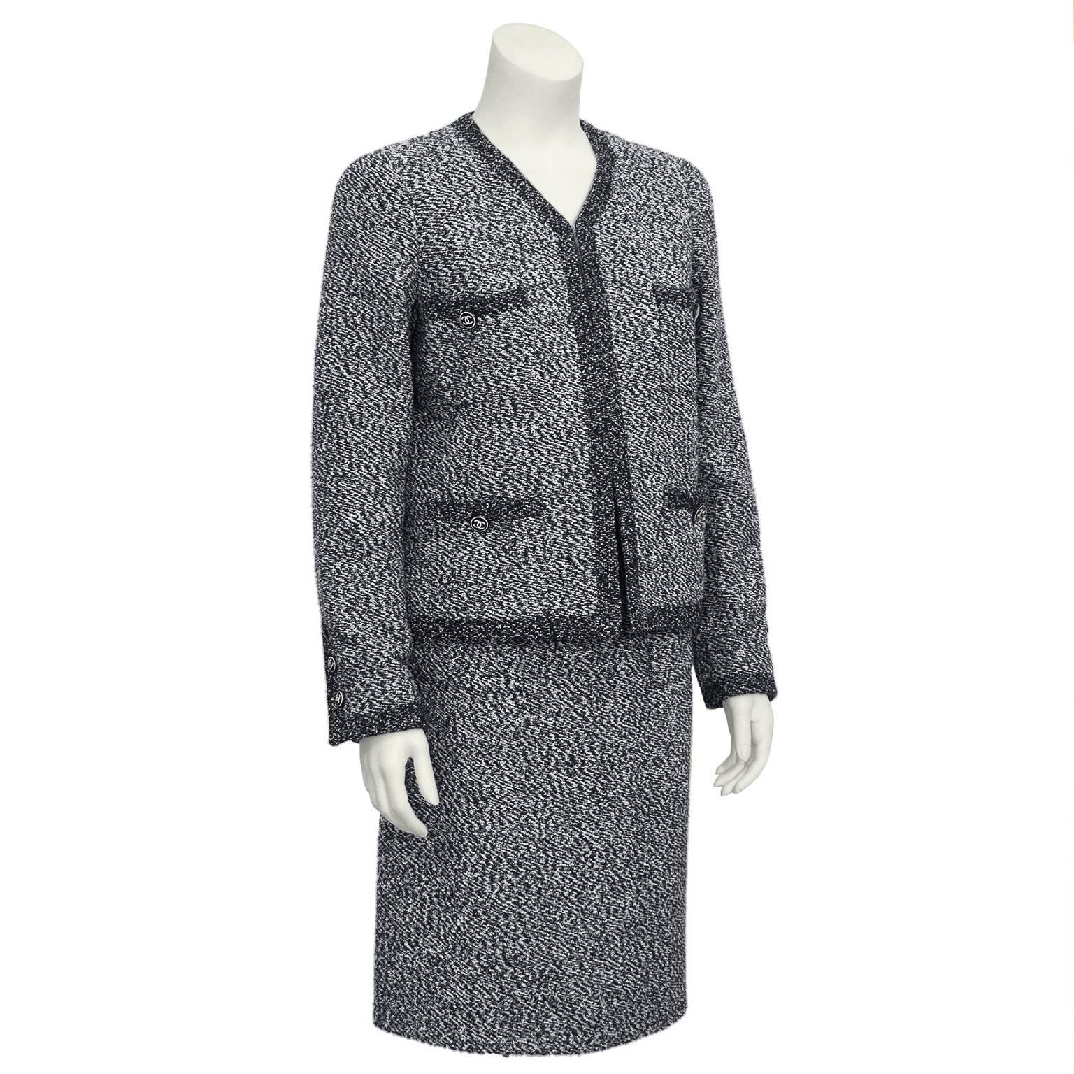 Iconic Chanel graphite tweed bloucle suit from the 1997 collection. Jacket is collarless with a darker trim. Four pockets on front side, each with a button. Three buttons on each wrist. Buttons are black resin with the Chanel CC logo in white. 