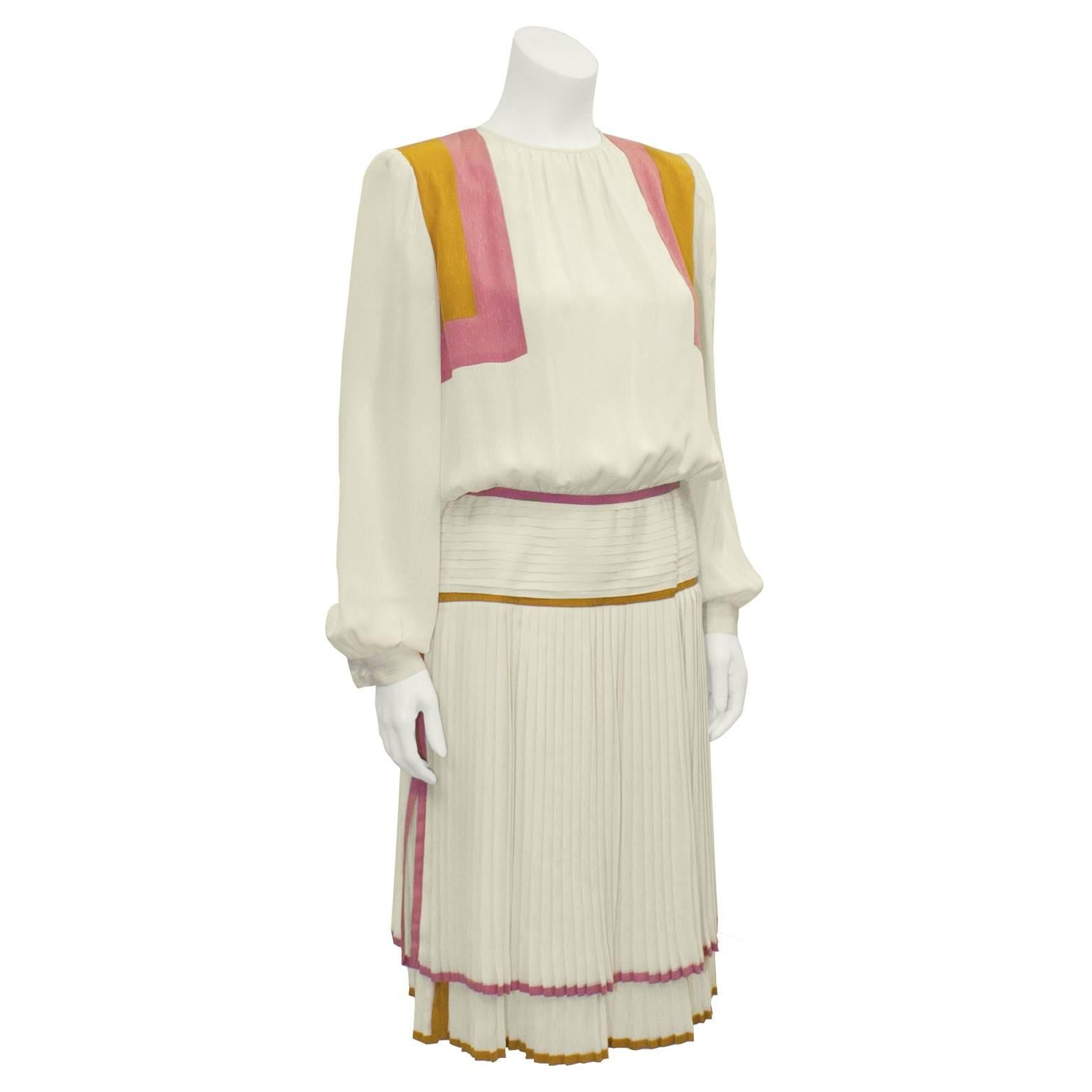 1980's Valentino silk jacquard dress with long sleeves and pleated skirt. A fabulous cream colored silk piece, with pink and mustard details. Slight gathering around jewel cut neck. Softly padded shoulders with loose fitting sleeves, and cuffed