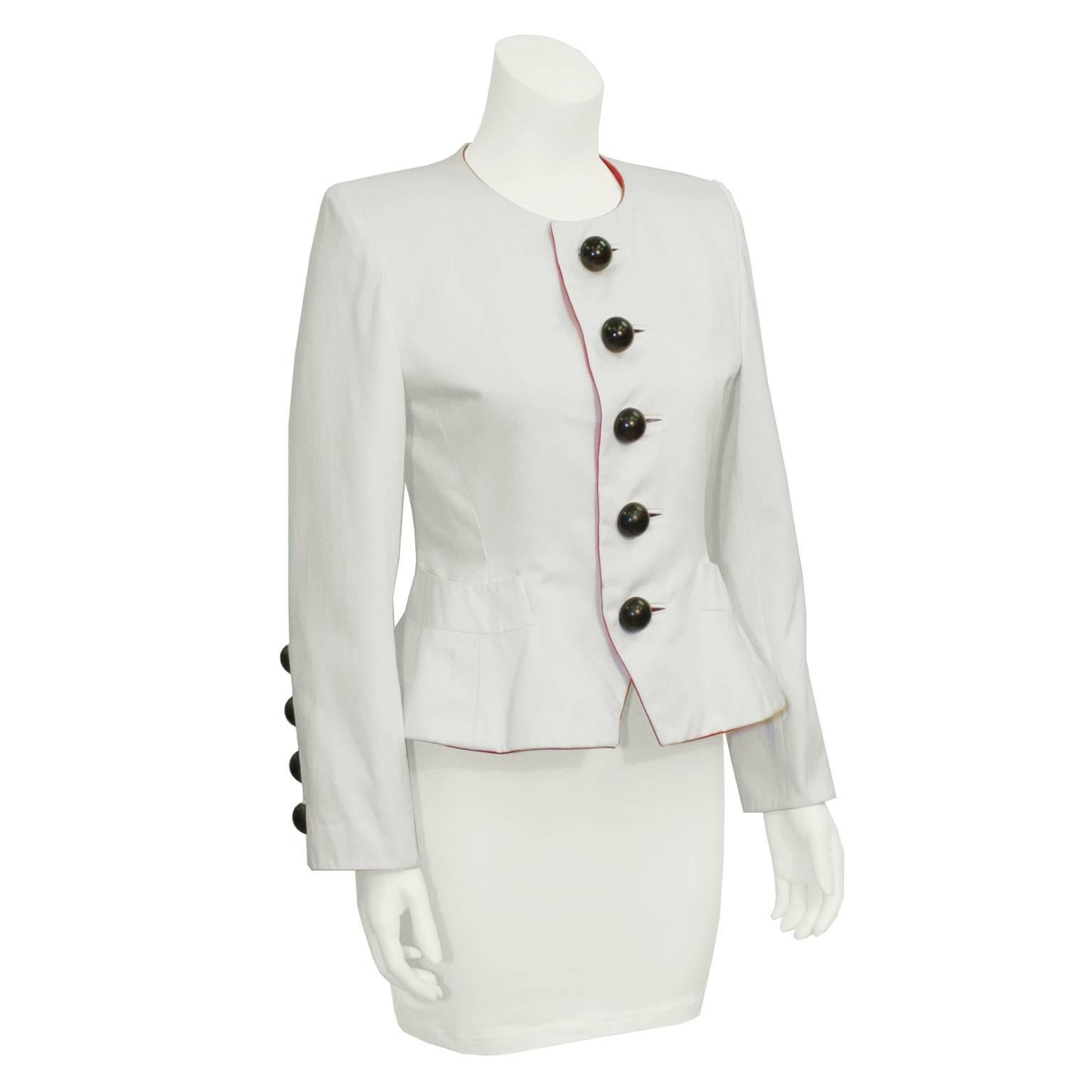 Chic Yves Saint Laurent white cotton jacket from the early 80's. Collarless, with large black dome shaped buttons down center and slash pockets on each hip. Both sleeves have four large dome buttons at wrist. Red interior trim with a ivory silk