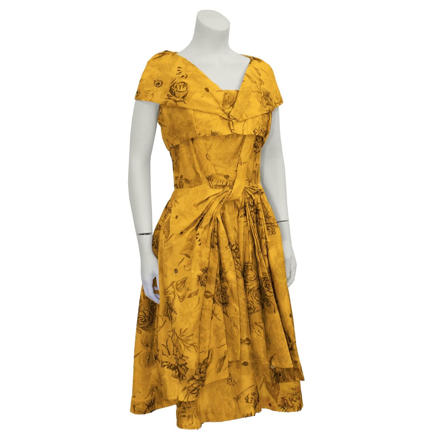 Adorable printed silk Suzy Perette dress from the 1950's, with a silhouette inspired by Dior's 'New Look'. Vibrant marigold color with a unique floral pattern, with brown details. Detachable mini bolero no longer available.  Cinched at the waist,