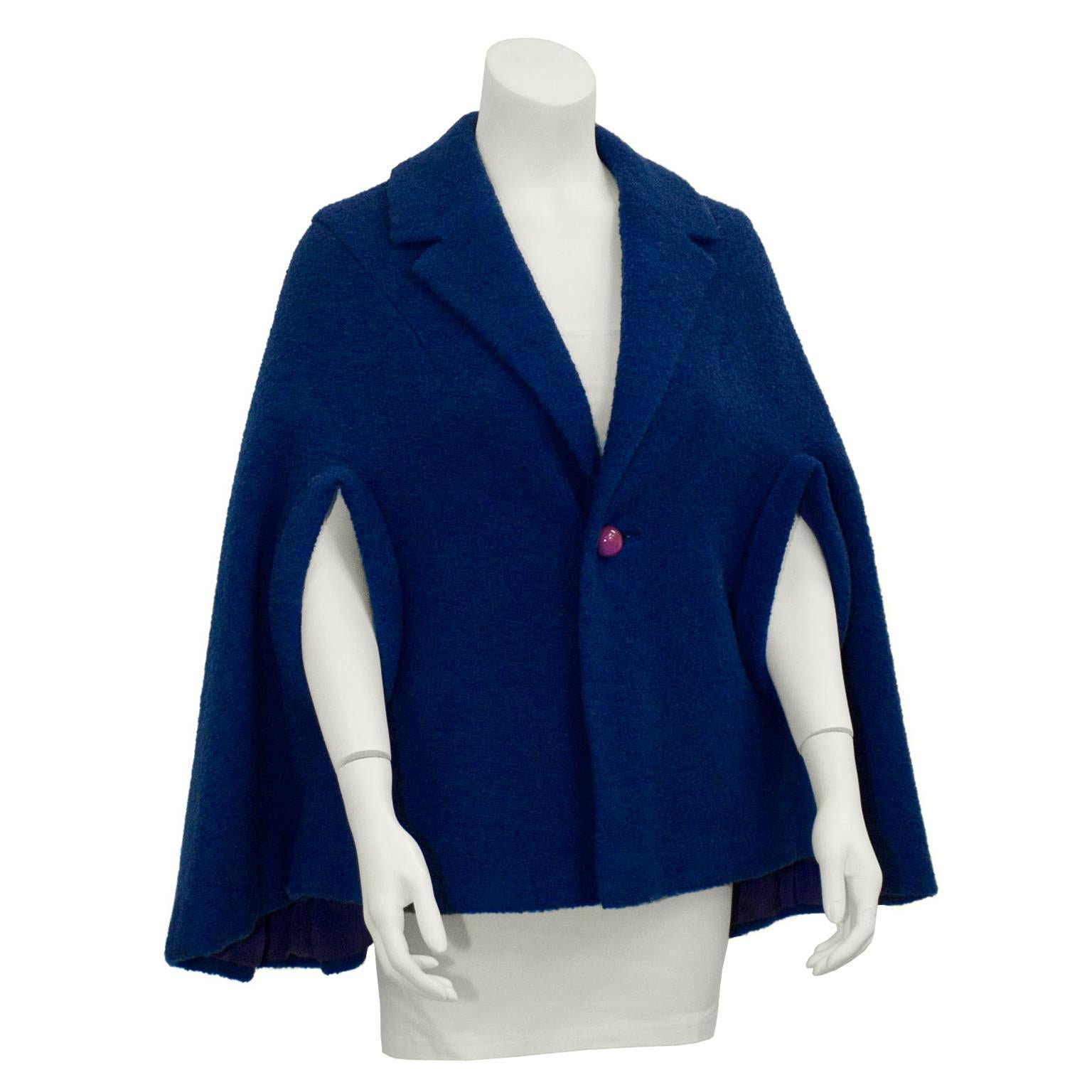 This anonymous blue boucle wool cape dates from the mid 1950's. It features a notched collar with a single button closure at center. Pink sphere button adds an adorable pop of color. A-line shape with pronounced seamed slits for arms. Excellent