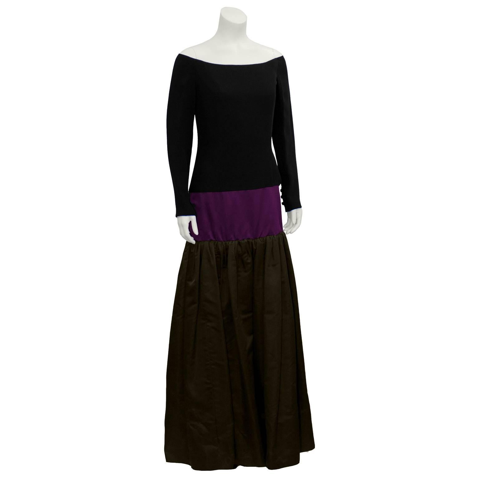 Sofisticado vestido Bill Blass tricolor sin hombros que data de la década de 1980. La parte superior del cuerpo es de punto negro. La falda de satén de color con cintura caída empieza en las caderas con una ancha banda morada. La capa más larga de