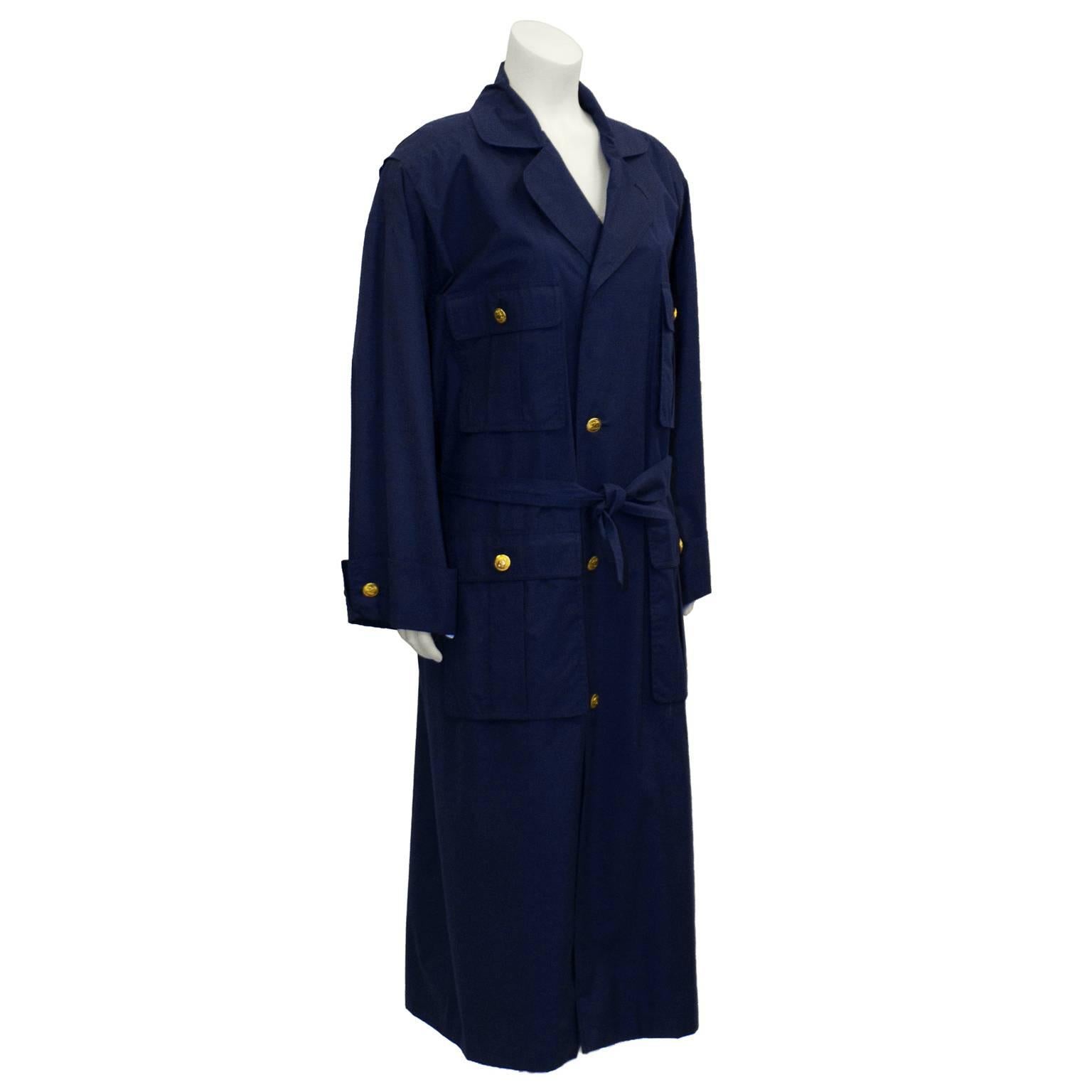 Stunning navy Chanel belted trench coat dates from the 1980's. Features notched lapels, front button closure, gold buttons with CC logo. Two vertically aligned oversized patch pockets on each side with single button on each flap. Loose fitting