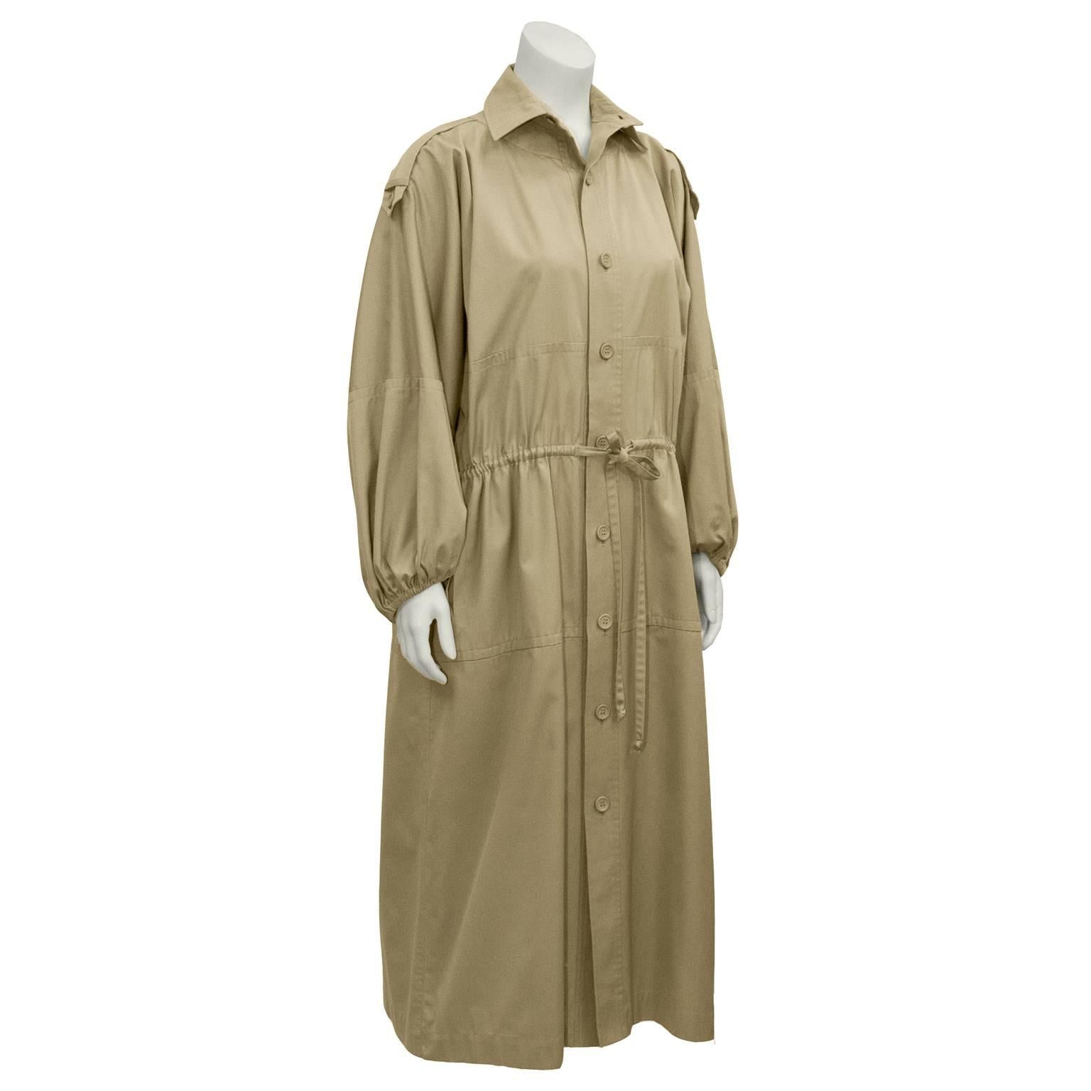 This amazing oversized Yves Saint Laurent beige cotton twill duster coat is a  piece from his safari collection in the 1970's. Shirt collar, drop shoulder with epaulets. Front button closure with plastic beige buttons. Sleeves are a loose lantern