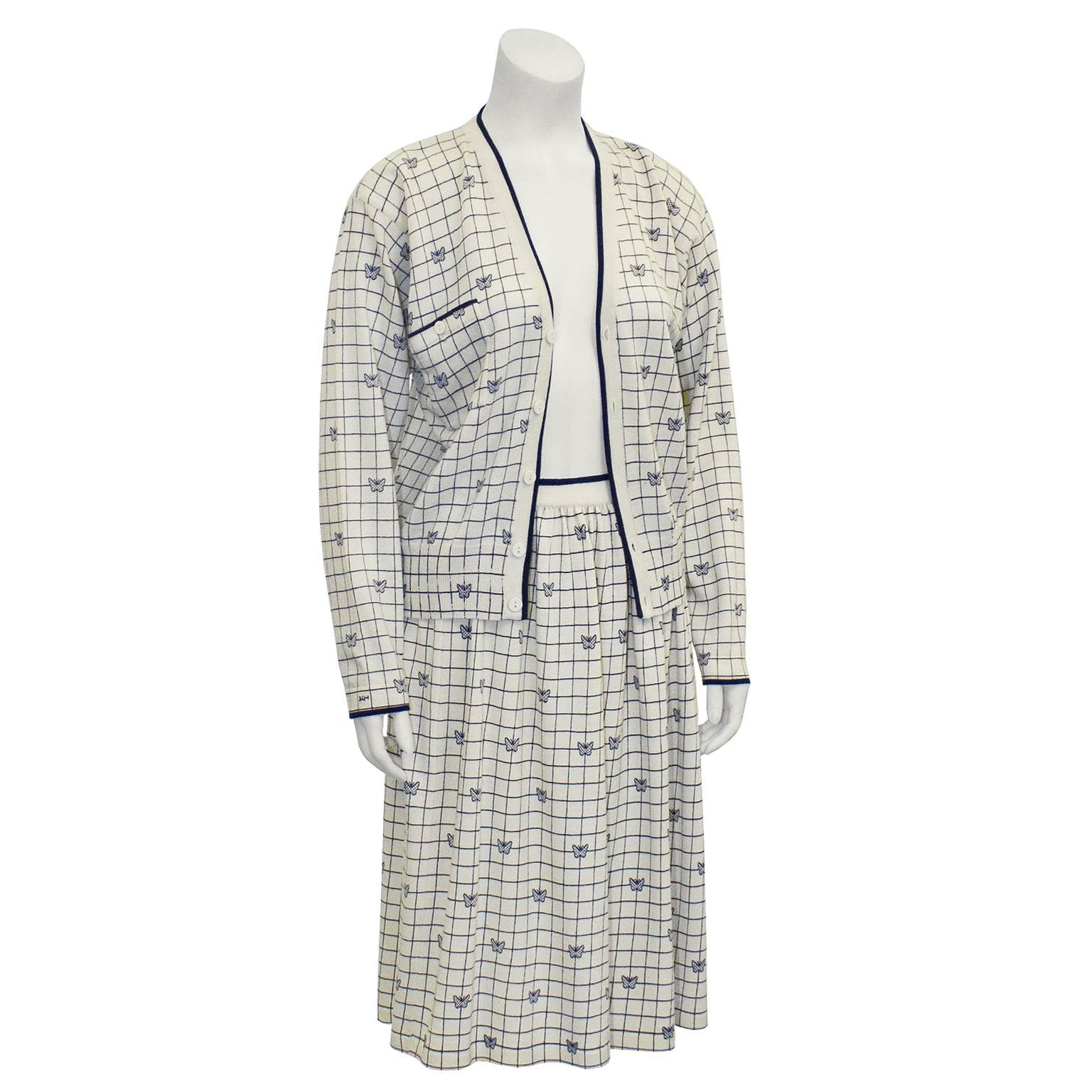 Adorable Krizia off white and navy fine wool knit set from the 1980's has a grid pattern with small butterflies on it. V-neck cardigan has a front button closure, and a breast pocket with single button. Plastic off white buttons. Narrow navy trim on