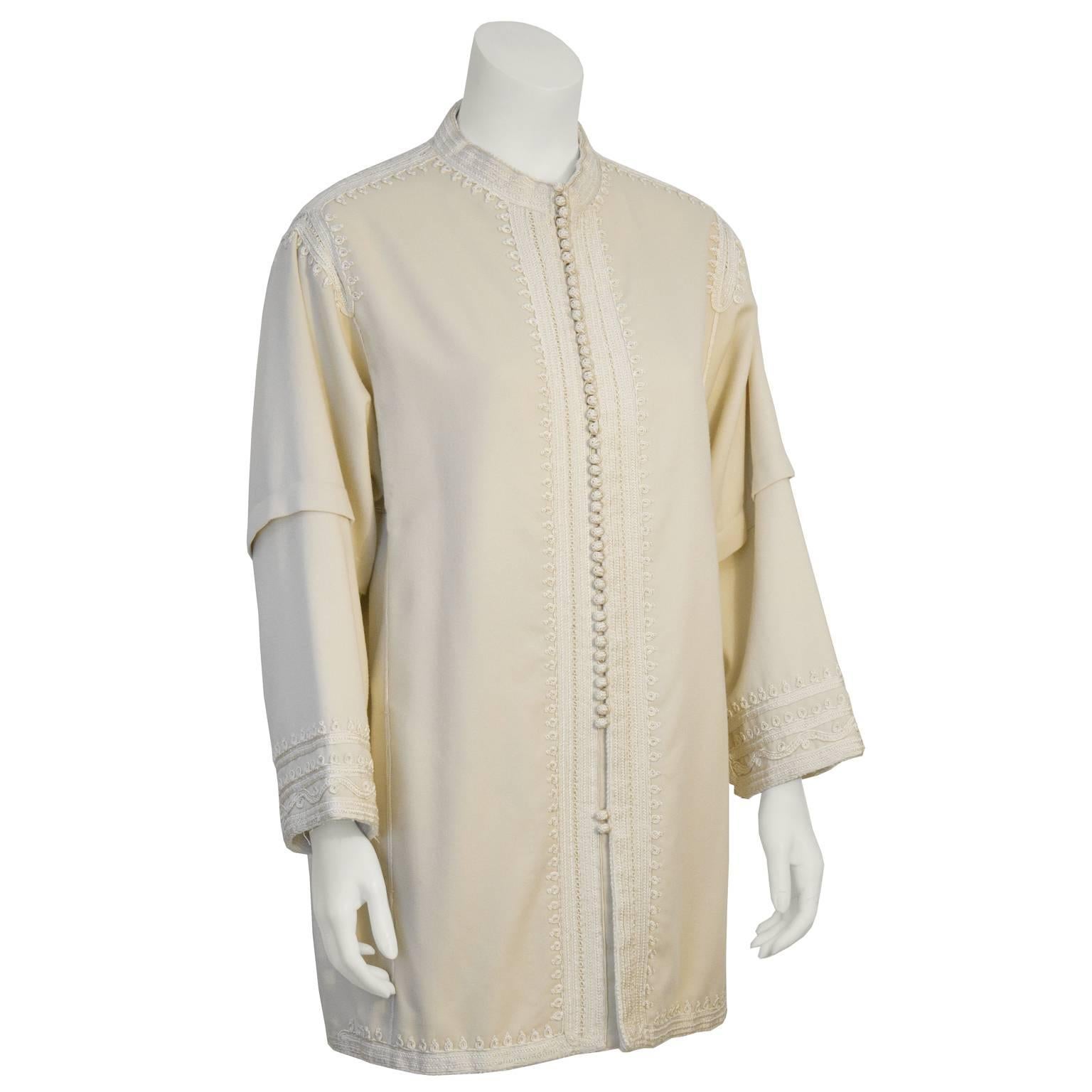 Stunning authentic Moroccan jacket with beautiful embroidered pasimentarie trim dates from the 1960's. Cream wool colored jacket is tunic length, with a band collar. Front button closure with several small loop buttons. Add diversity to your