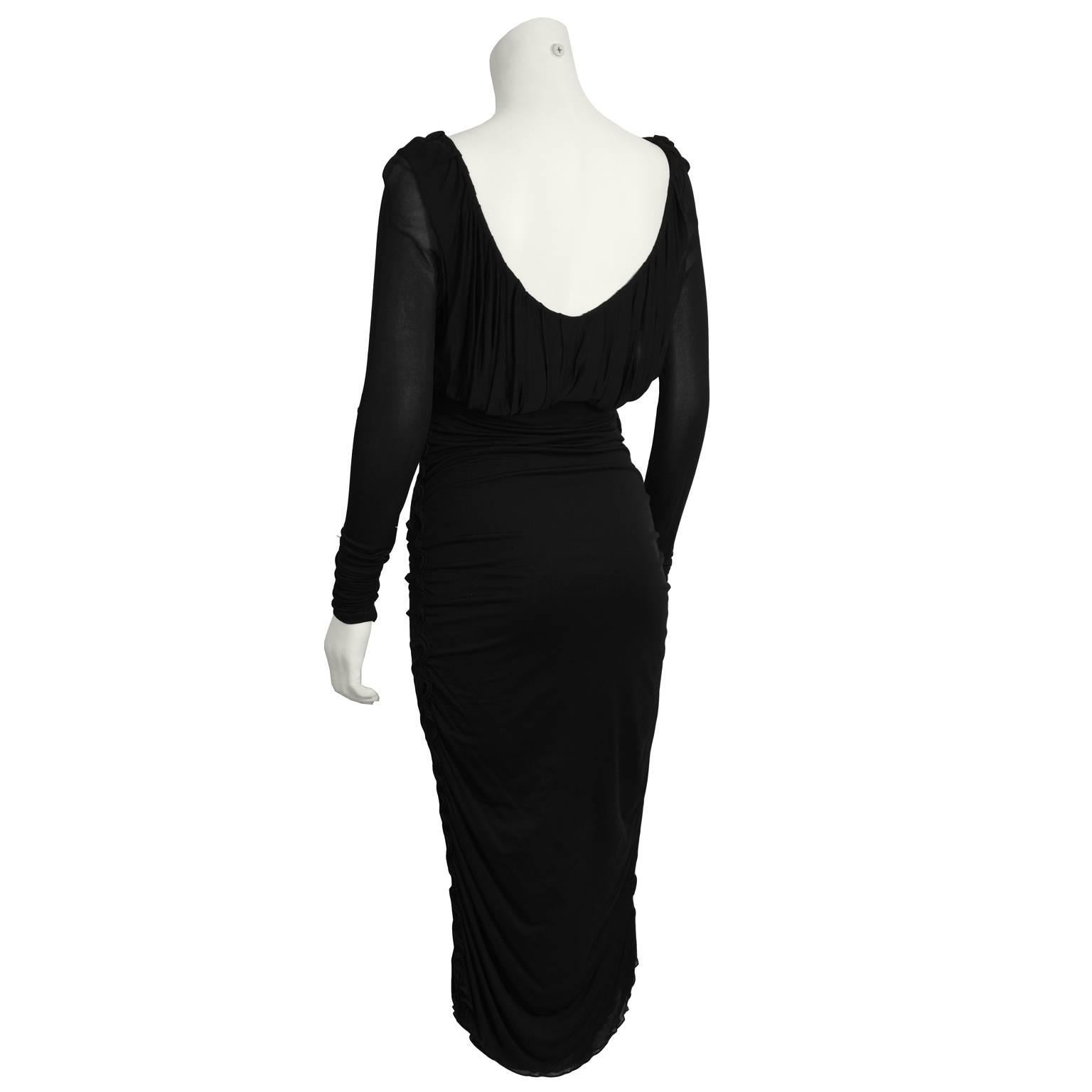 Fabulous Gucci long-sleeved ruched black jersey cocktail dress from the 2000's. This sleek body con dress has a deep scoop neckline with a loose fitting bodice, and gathered detailing on the sides. Lightweight. Stretch fit. Midi-length ensures a.m.