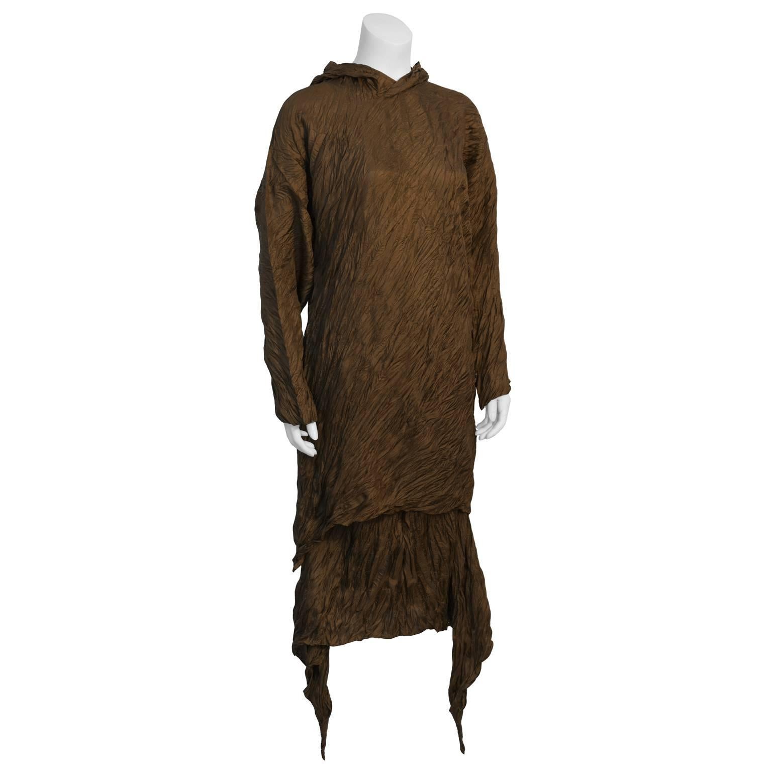 Amazing Issey Miyake brown signature crinkled polyester top and skirt duo from the 1980's. Crinkled long sleeve pullover is tunic length with a pointed hood. Mid length skirt has elasticized waist and hanging hanky hems that can be tied or left to