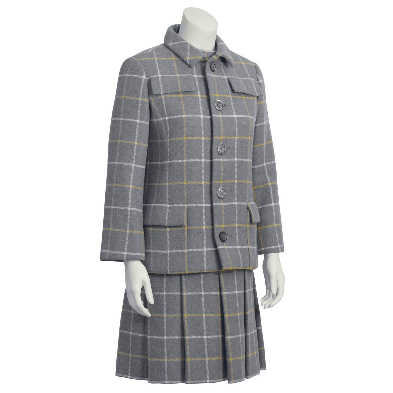 Chic 1960's grey windowpane wool dress and jacket duo features a sleeveless band neck dress with two vertical slit pockets at the waist and a box pleated drop waist skirt. Jacket has flap pockets at each breast and patch pockets at the hips. Front
