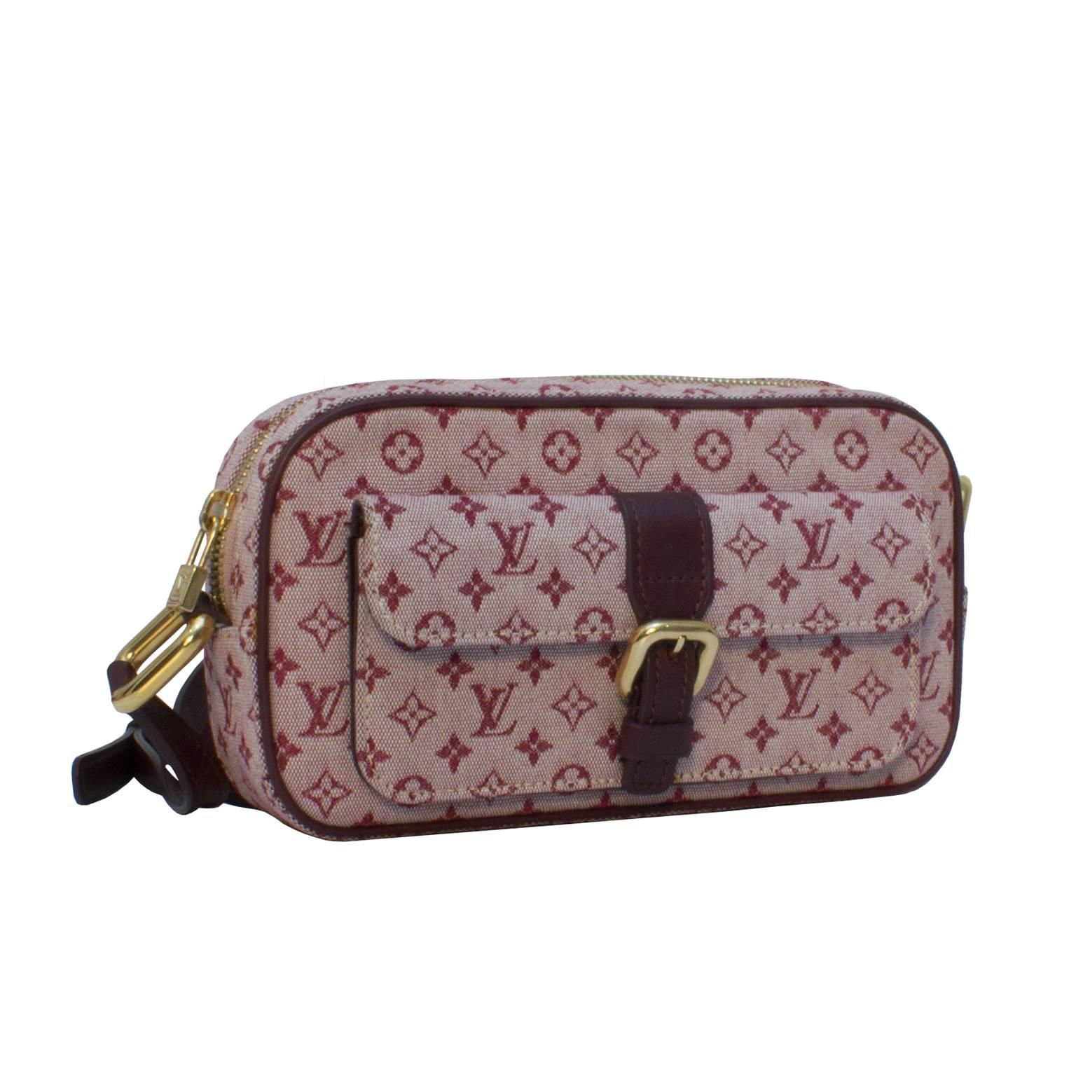 Chic Louis Vuitton bordeau monogram mini camera bag features a canvas body, a dark brown leather cross body strap, leather trimming, and a front flap pocket with a leather buckle. Beige canvas interior lining. Top zip closure and gold tone hardware.
