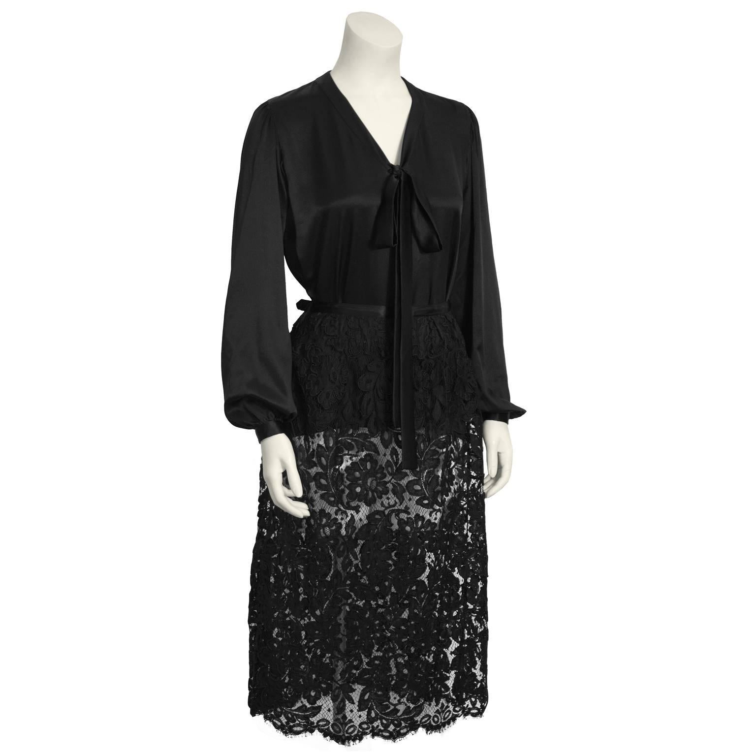 Classic Yves Saint Laurent duo from the 1970's features a black silk tie-neck blouse and a chic black guipure lace skirt.  Blouse is long sleeve with slight gathering at the shoulders and wrists. Cuffed wrists have single button. Mid length pencil
