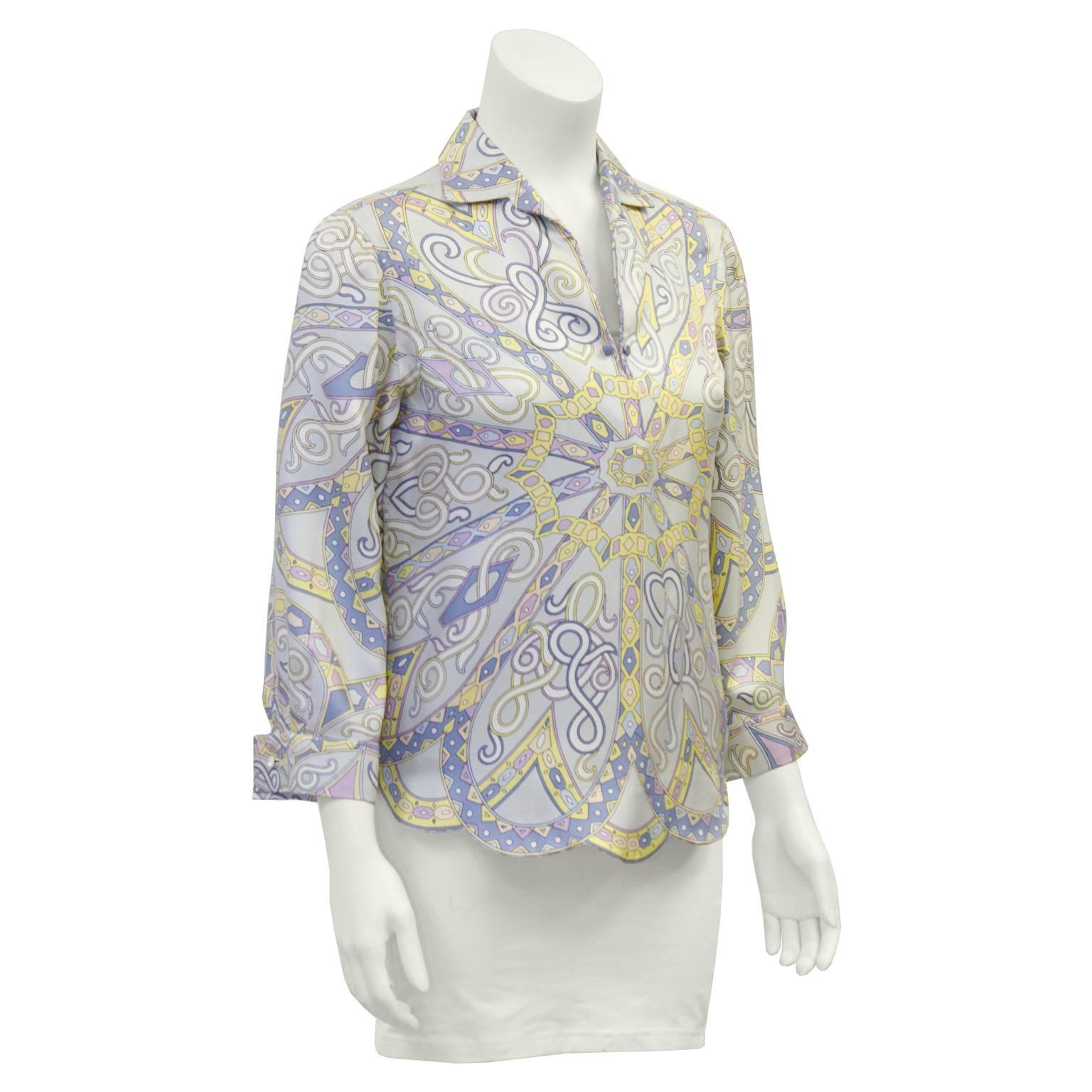 Gorgeous Emilio Pucci multi colored silk blouse from the 1970's, featuring a fabulous detailed print in light pastel blue, pink, yellow and purple. Shirt collar with a plunging V neckline. Cuffs have single button on them. Scalloped hemline adds a