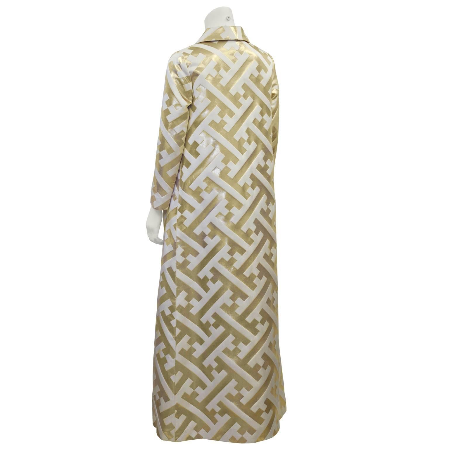 Dazzle in this anonymous gold and white evening coat dating from the 1960's. Floor length, A-line cut, with notched lapels and a front fabric button closure. Features unique all-over pattern in white and a shiny gold. The perfect coat for a black