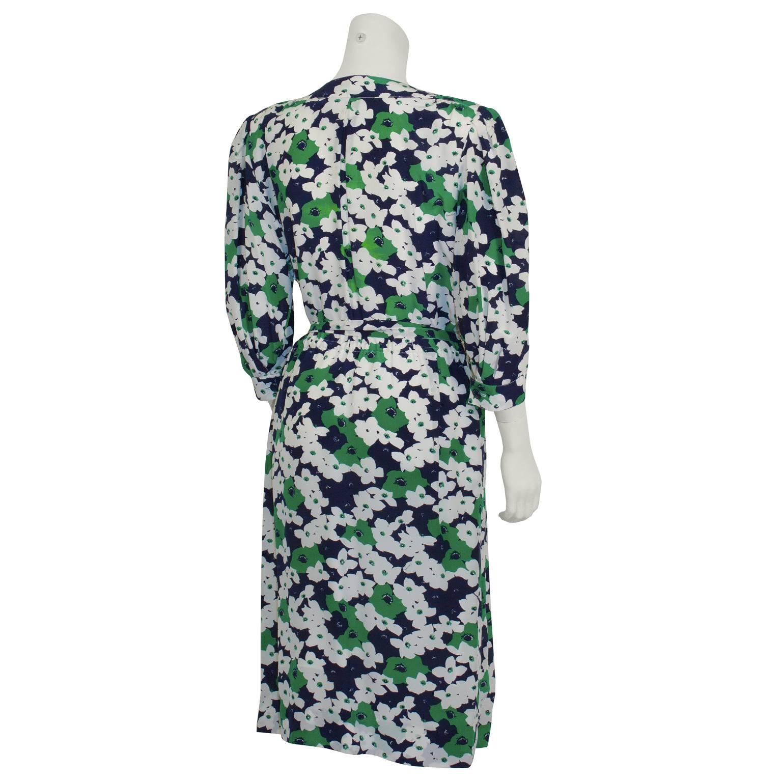 Chic 1980s Celine silk floral day dress featuring a scoop neck, front button closure, padded shoulders, three quarter length sleeves, and a tie up waist belt. Floral pattern in colors navy blue, green and white. A lovely addition to your spring