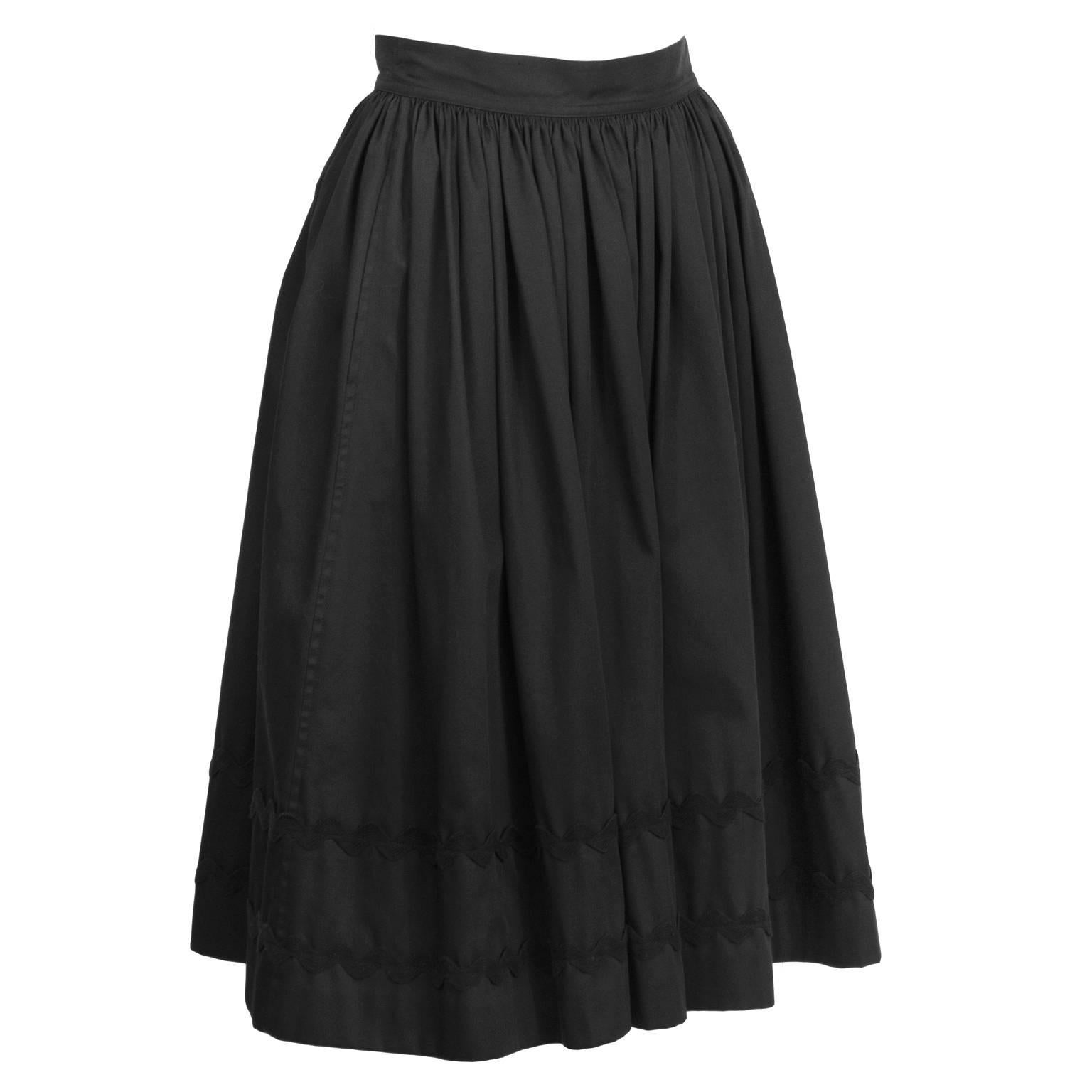 Very cute black cotton Yves Saint Laurent dirndl style skirt from the 1970's. Cinched at waist, with a full a line, softly gathered skirt. Two rows of black rickrack ribbon detail at bottom. Excellent vintage condition. Fits like US size 4.