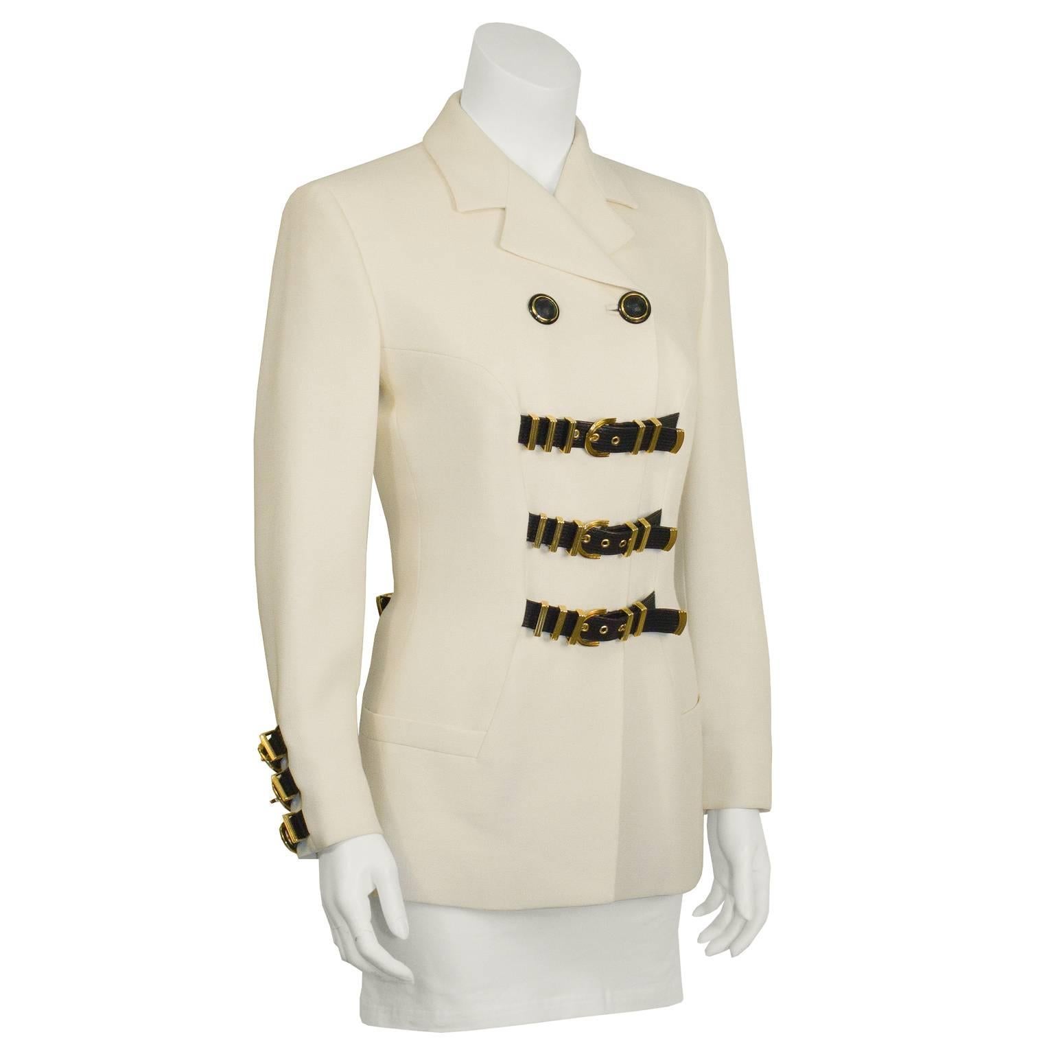 1980's vintage Versace cream wool gabardine blazer with bondage belts detail on the front, three on each sleeve, and a crisscross on the back. Constructed with notched lapels, a double front button closure and two slit pockets. Black leather belts