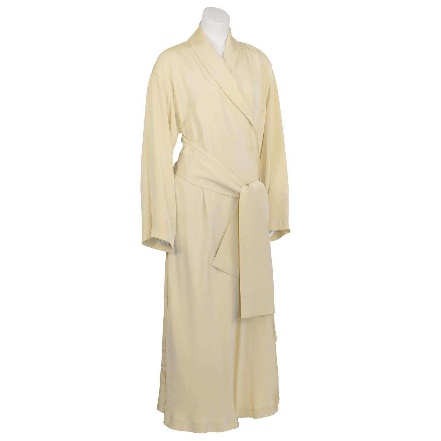 Elegant and unique vintage Issey Miyake cream silk robe style dress from the 1980's featuring a shawl neck, slightly gathered shouldered, loose sleeves, and an asymmetrical hem. Extra wide attached belt can be tied in multiple fashions. Excellent