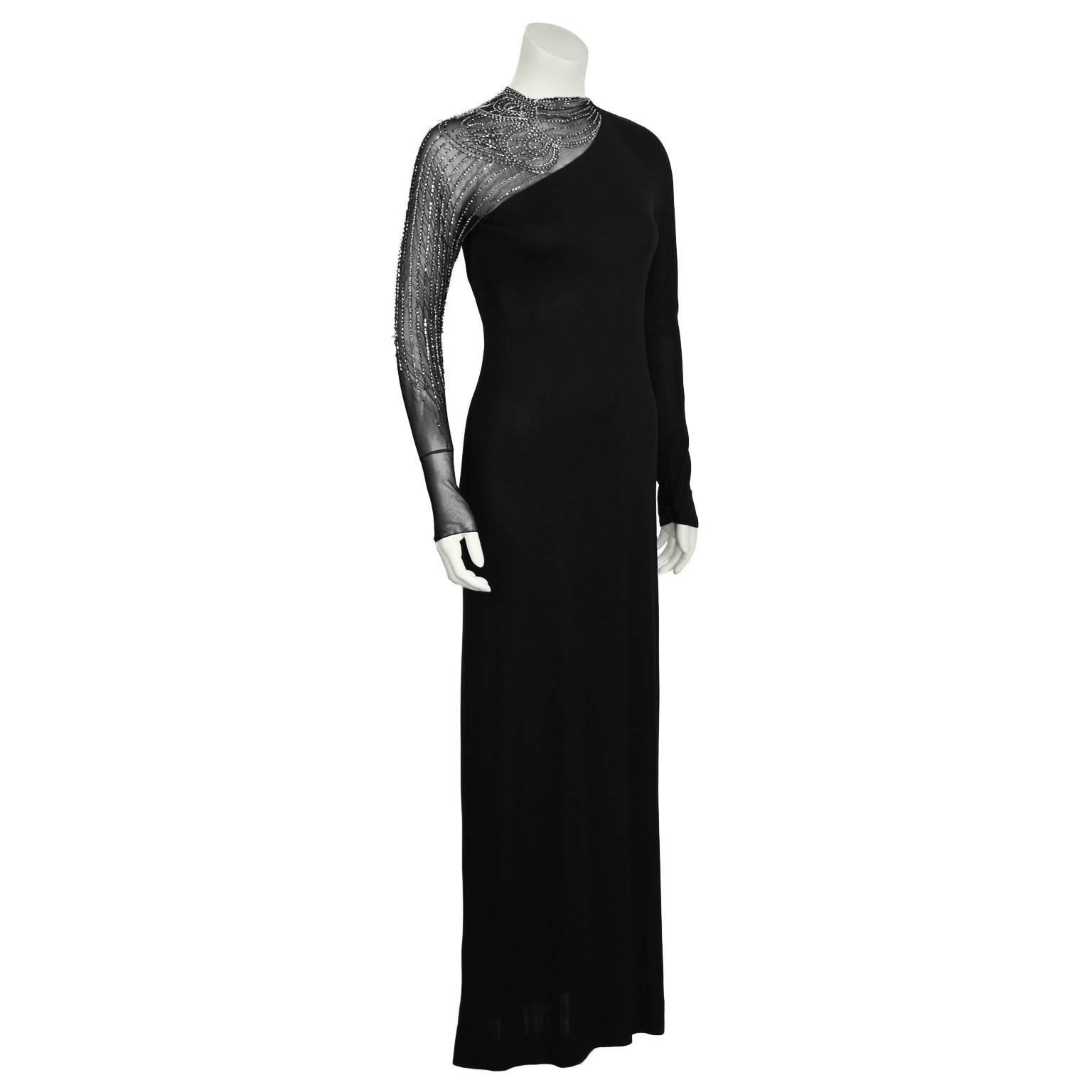 1950's Mollie Parnis black rayon and chiffon long sleeve gown with unique asymmetrical shear chiffon and beading shoulder. The intricate beaded pattern, made up of rhinestones and bugles, cascades down the arm. Zipper and hook in the back. Small