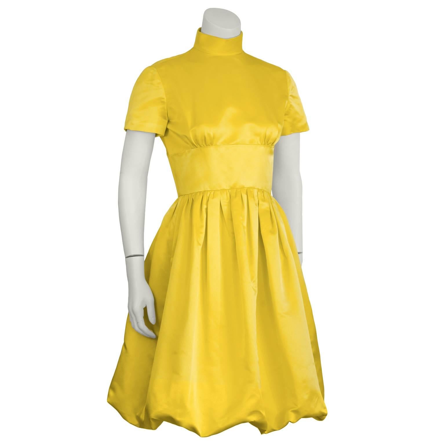 Stunning 1960's yellow satin bubble hem cocktail dress made for I Magnin's couture studio featuring a raised band collar, short sleeves, a wide fitted waist with a full gathered skirt. Fastens with fabric covered loop buttons and hidden snaps.