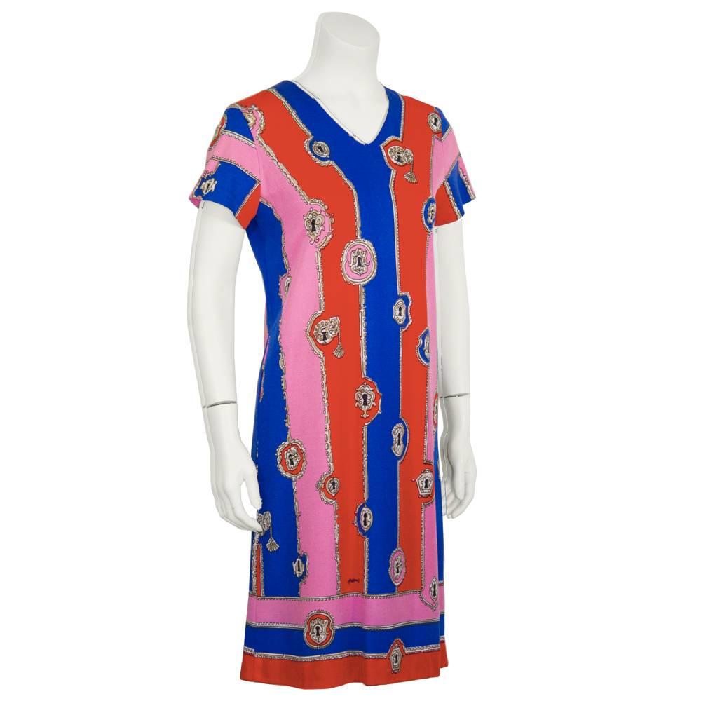 This adorable1970's polyester Artemis mini dress is a soft A-line cut with a v neck, and short sleeves.  Red blue and pink striped pattern is detailed with a lock and key motif. In the style made popular by Emilio Pucci this wash and wear fabric is