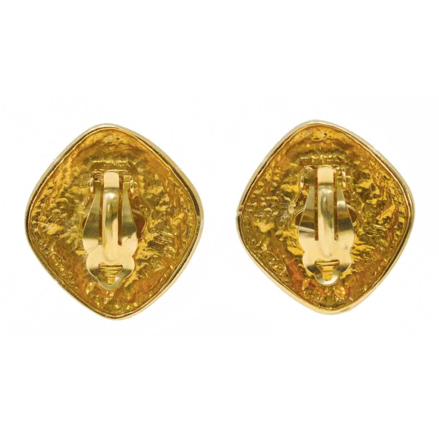 Early 80’s Chanel diamond shape clip-on earrings with center pearl. Textured gold tone surrounding decorated a ball and swirl pattern. Excellent condition.