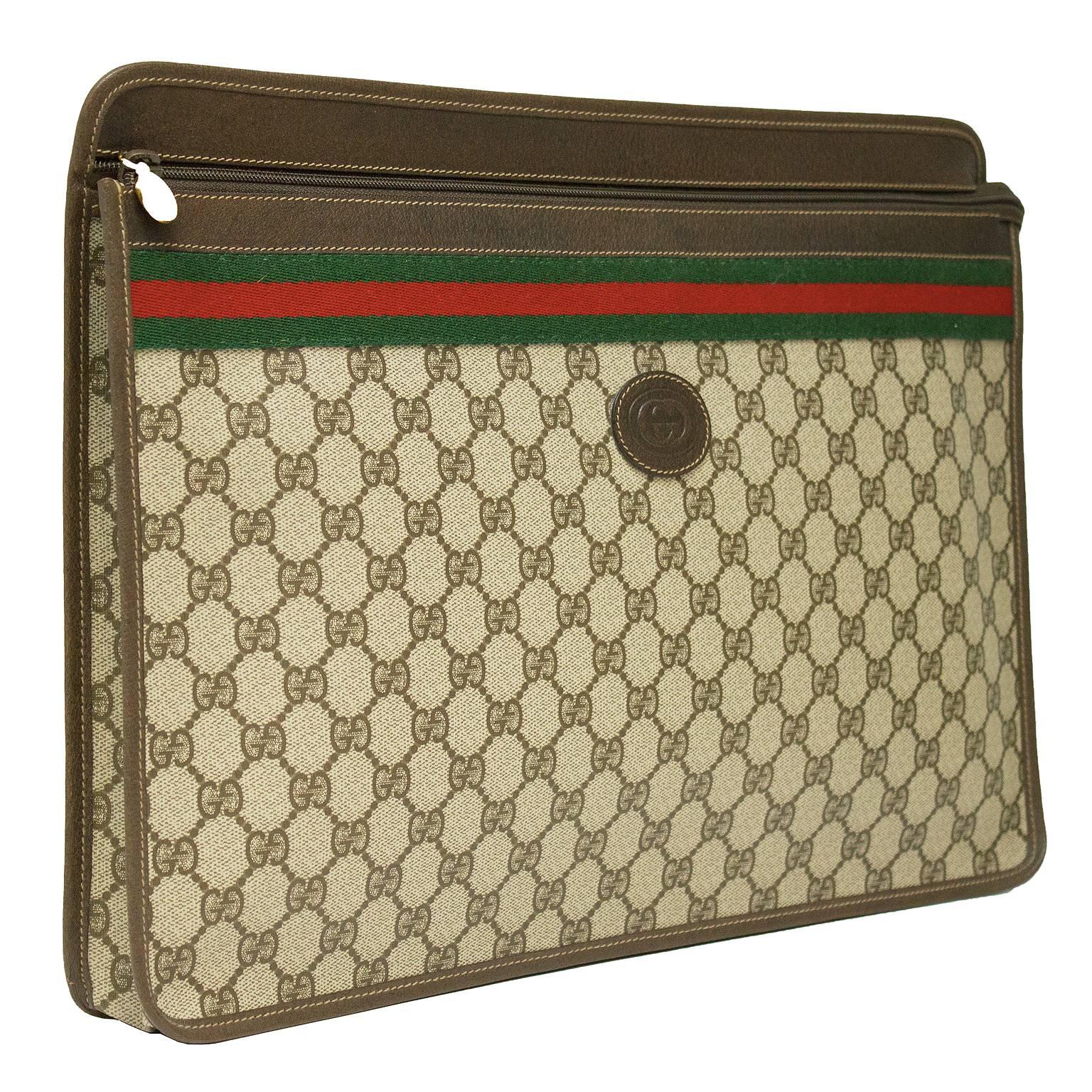 Pristine 1970's Gucci vinyl treated canvas zip top portfolio. Top of the bag is framed in brown leather with the iconic Gucci red and green striped ribbon beneath. The zipper, with a gold Gucci pull tab, extends past the bag and fastens to the back
