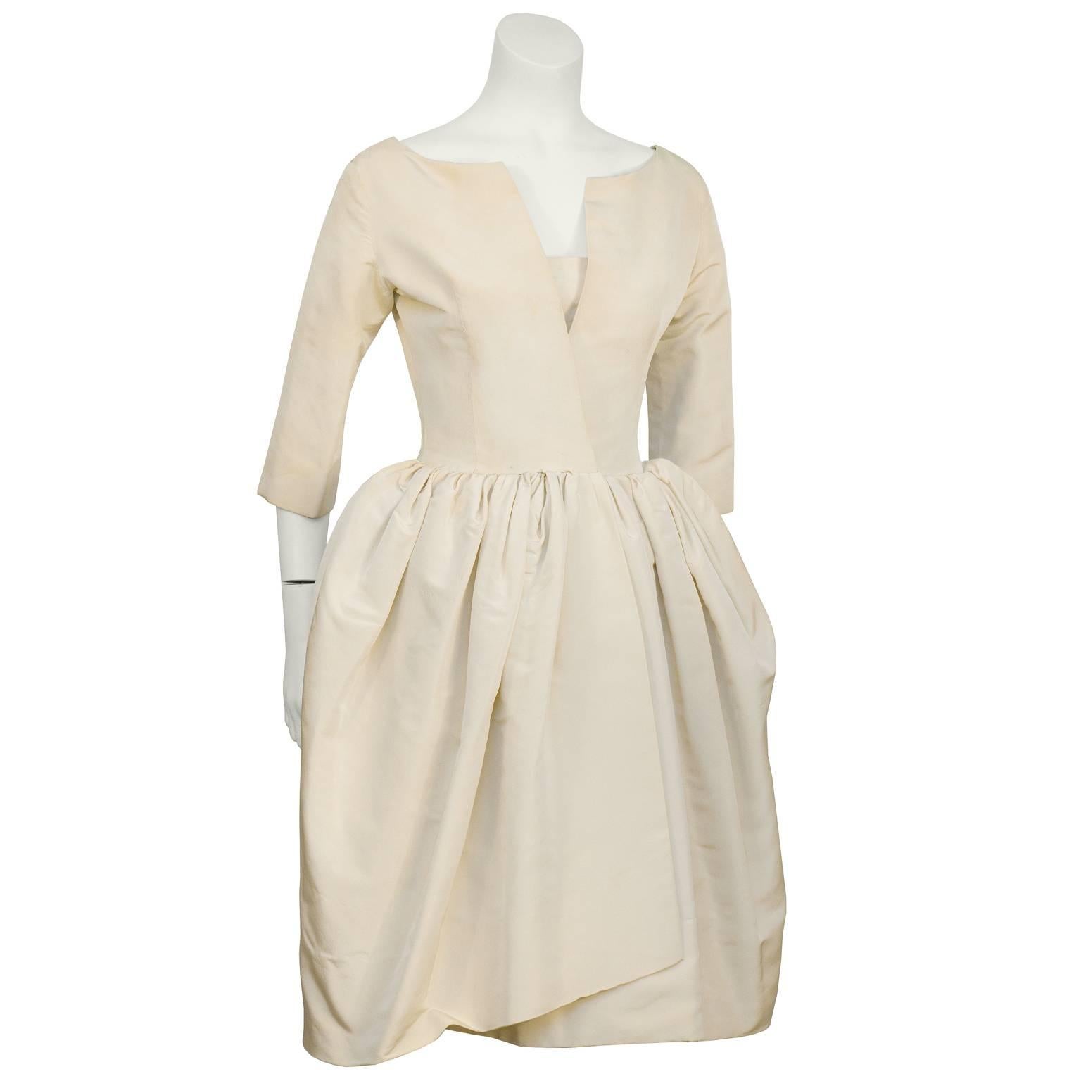 Pre 1957 Christian Dior beige silk robe de soir cocktail dress.  Unique example of one of the first French couture partnerships with a North American luxury department store. All hand stitched. Fitted waist with a slit overlay neckline with half