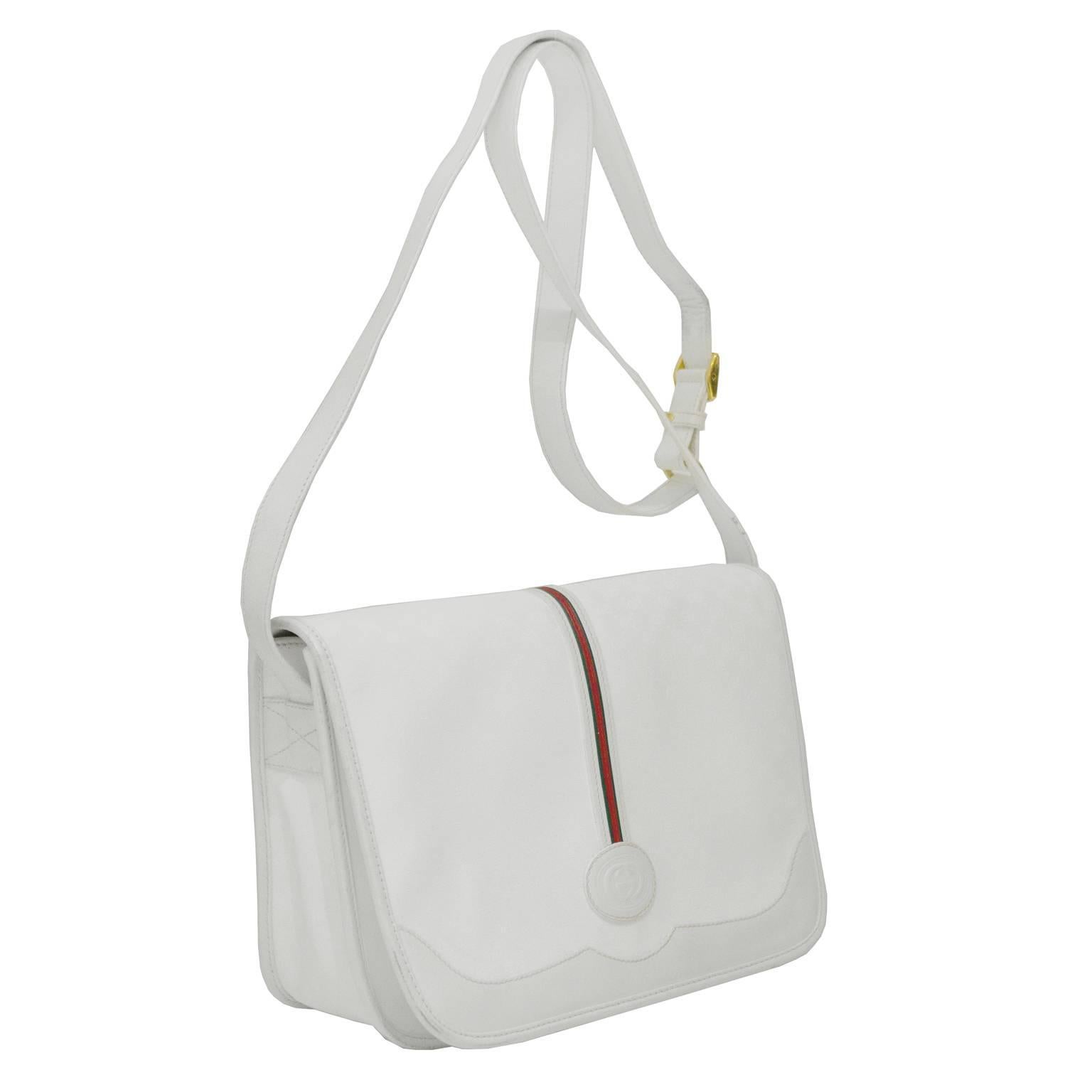 1970's Gucci white coated canvas and leather messenger bag with a long adjustable cross body strap. Constructed of grey on white signature monogram canvas trimmed in a smooth white leather. Large flap is decorated with a vertical red and green