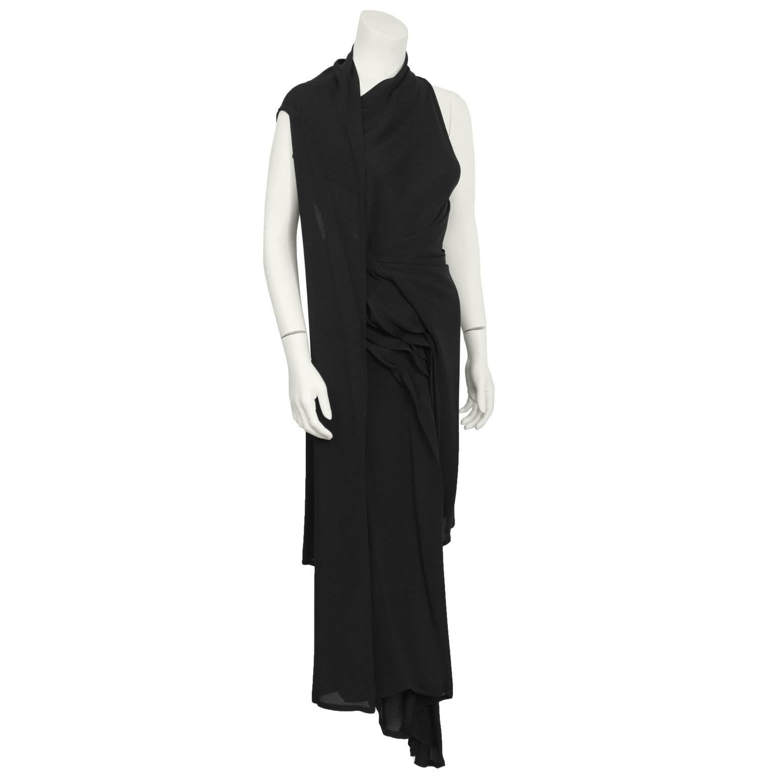 1990's Anne Demeulemeester black crepe convertible draped cocktail dress. Fastens with a single snap button at the neck. Sleeveless design with an asymmetric neckline, a tie waist and asymmetric draped fabric. Excellent condition.  Forgiving fit