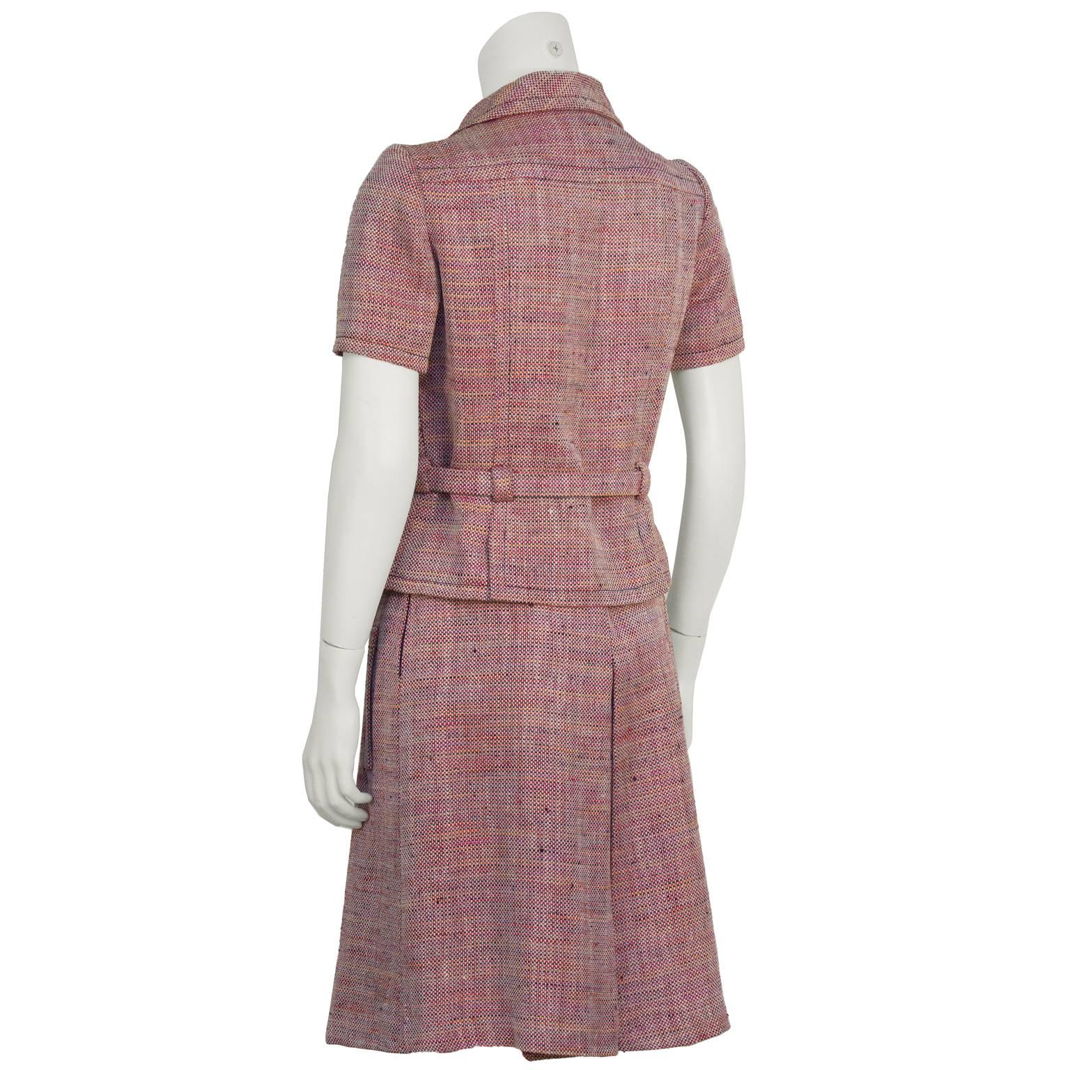 1960’s Guy LaRoche red, pink, orange and blue rayon tweed short sleeved skirt suit. The jacket features a fully adjustable belt at the waist with pewter metal buttons down the front. Skirt has an inverted pleat on the front and back and two banded