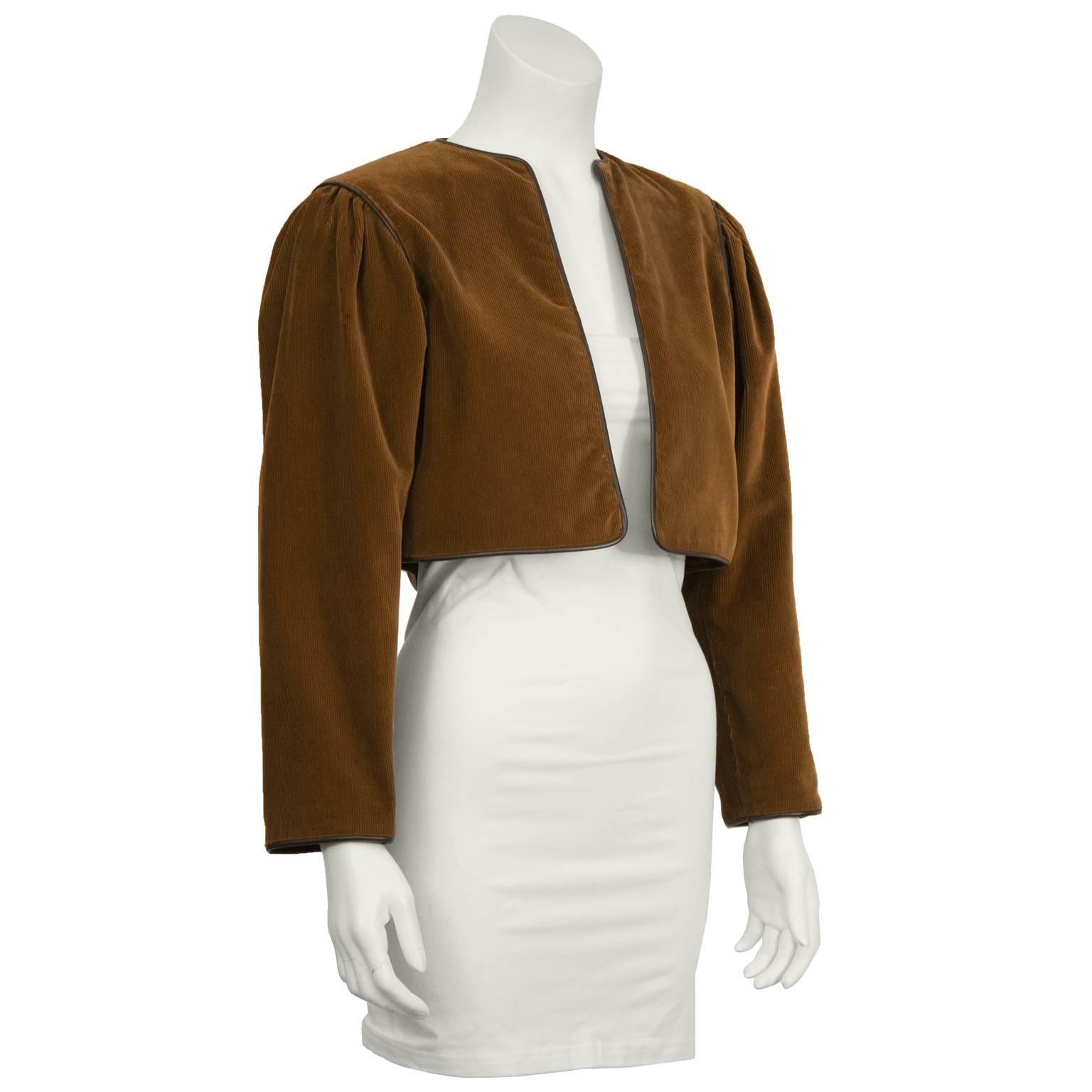 1970's iconic Yves Saint Laurent cropped brown corduroy bolero jacket with dark brown leather piping. Slight gathering at shoulder and lined in brown satin. In excellent condition. Fits like a US size 2-4.