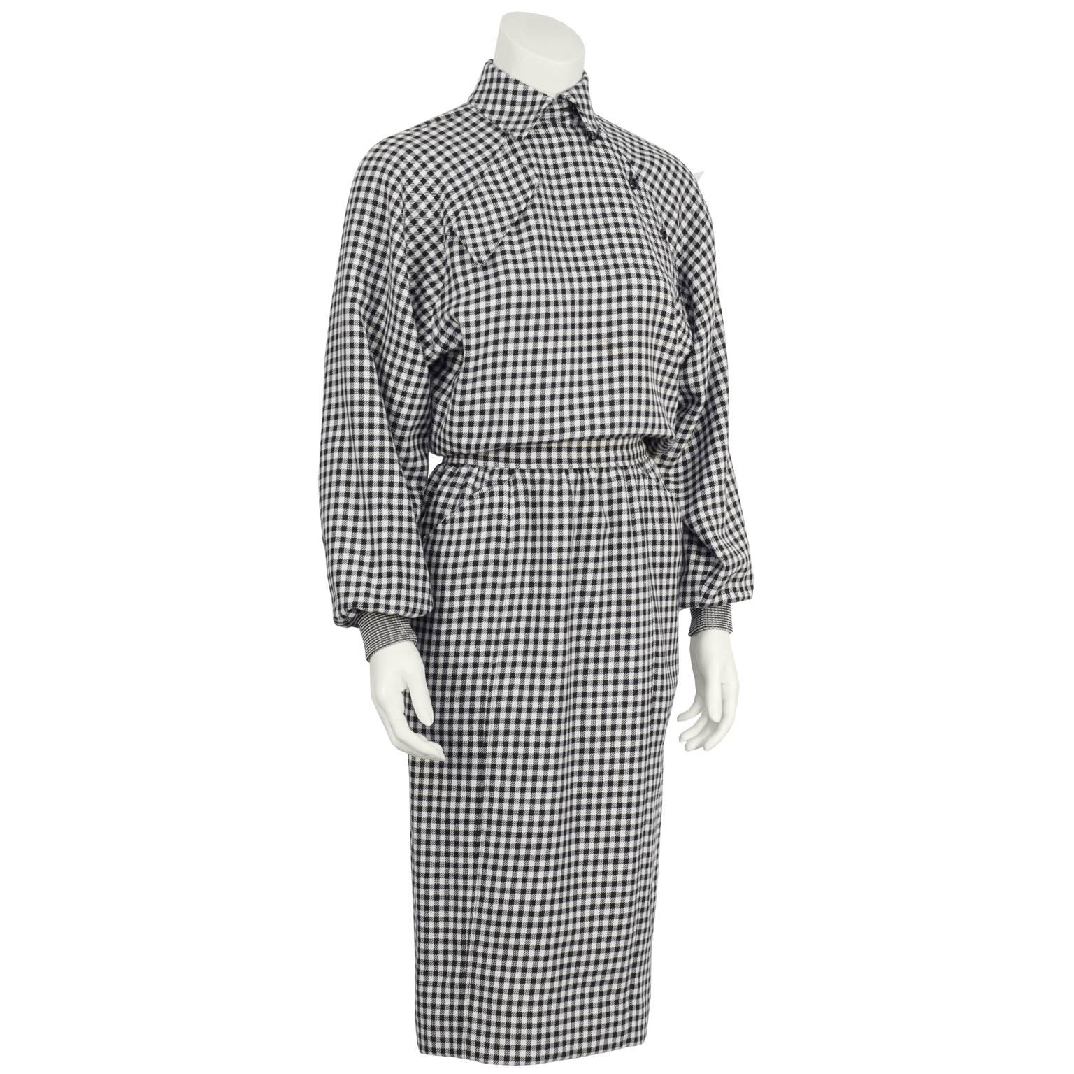 Ungaro wool blend black and white houndstooth dress from the 1980’s. Styled with an asymmetrical button-up neckline with a faux flap pocket on the opposite breast. Batwing sleeves are finished with ribbed knit cuffs. The pencil style skirt has
