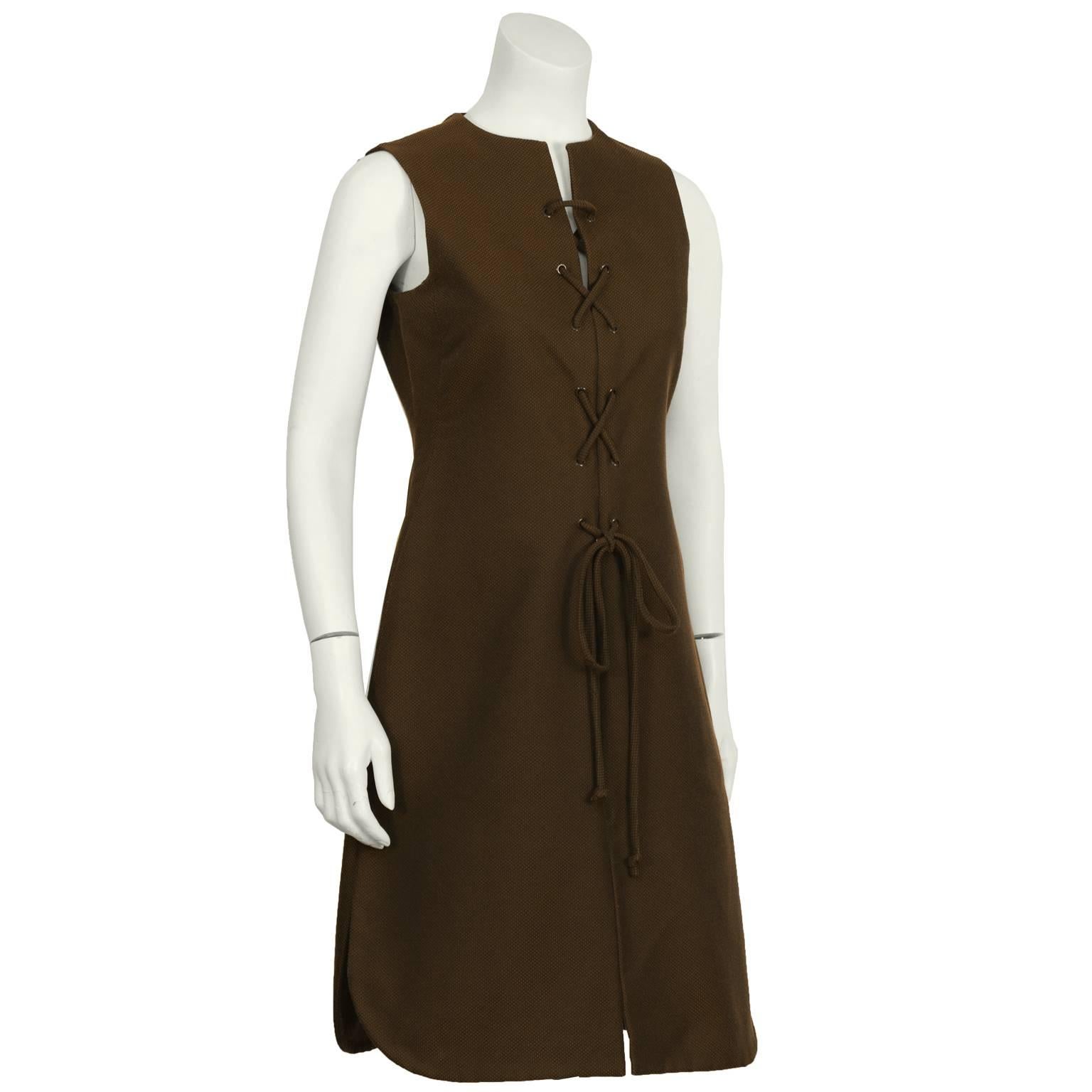 Early 1970’s Geoffrey Beene chocolate brown  cotton pique lace front day dress. The sleeveless slit neck dress features brown metal grommets around the front that allow for easy lacing. Slit in the front. Hem finished front and back tunic style with
