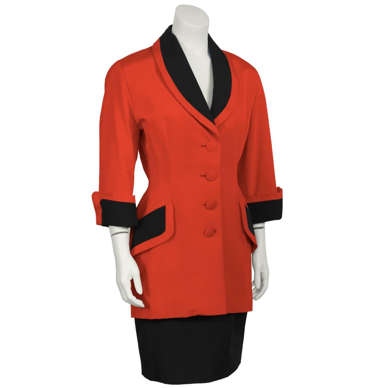 Isabelle Allard red skirt suit from the 1980's. The red jacket is fitted through the waist and features a black lapel, cuffs and pocket flaps. Covered red buttons down the front and the jacket falls to below the hip. The black skirt is meant to be