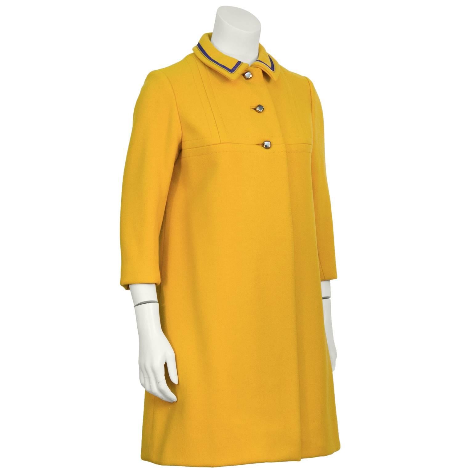 Anonymous marigold wool coat from the 1960's. The petite coat features a seamed yoke and unique pewter square buttons on the front. The collar is piped in a purple and gold ribbon detailing. Finished with a matching button at the back of the neck.
