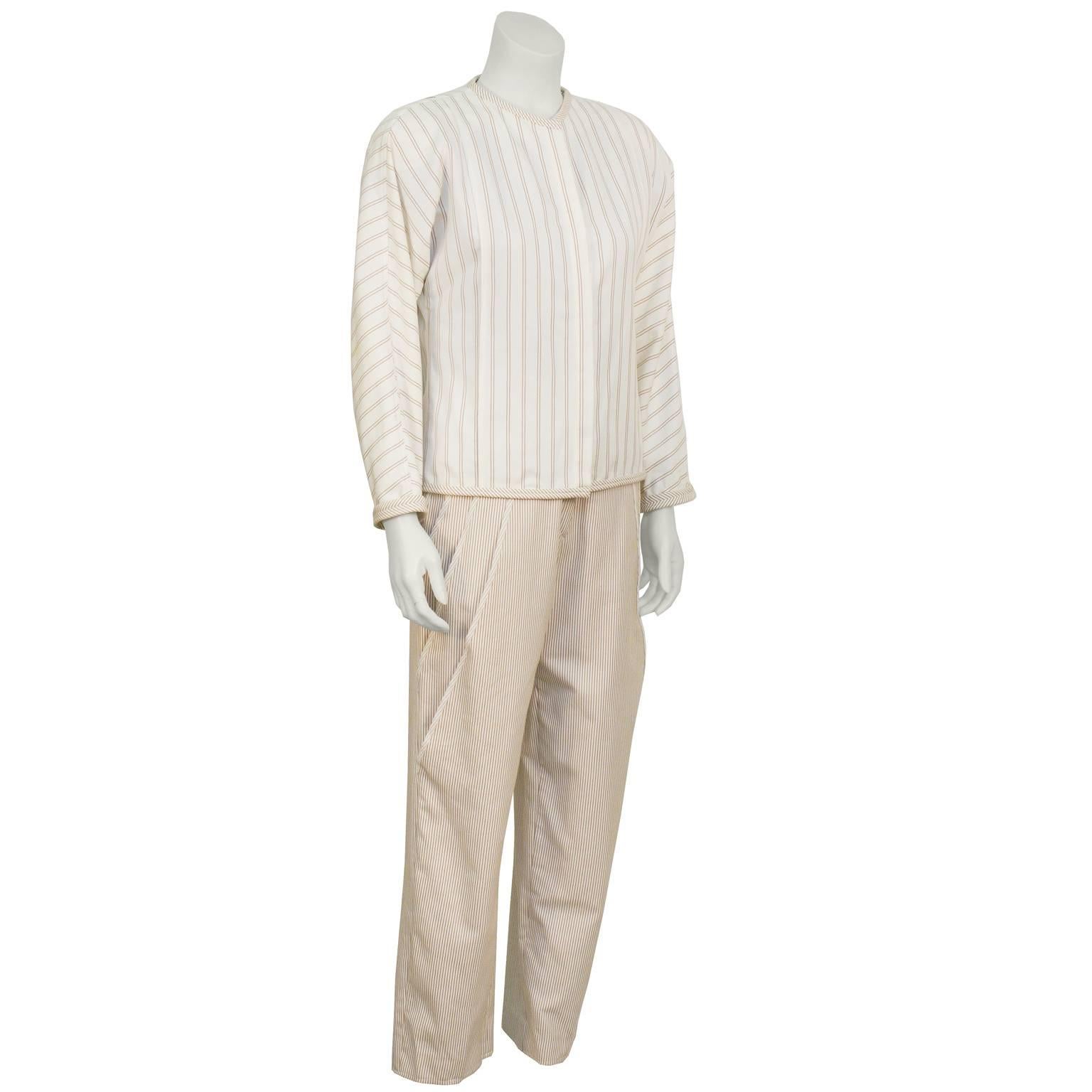 Gianni Versace cotton and linen suit from the late 1980's. The collarless cream jacket is covered in a taupe horizontal line patterned fabric and is banded at the collar, hem and cuffs in a similar fabric. Closes with buttons down the front. The