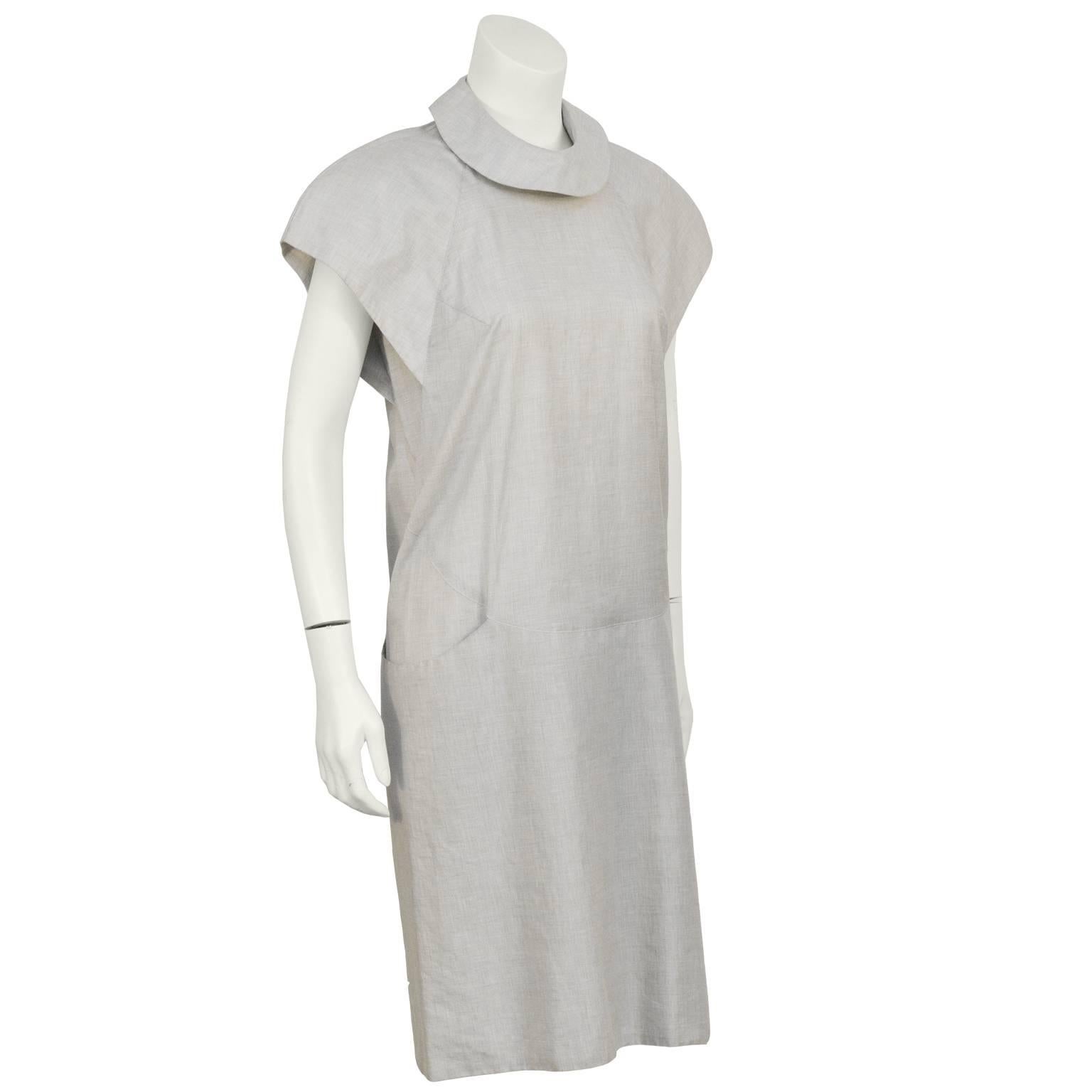 American mid 80's designer Catherine Hipp light grey cotton drop waist day dress. The dress features a circular collar with two loop buttons that fasten at the back and winged capped sleeves. The two large side pockets wrap around the hip creating a