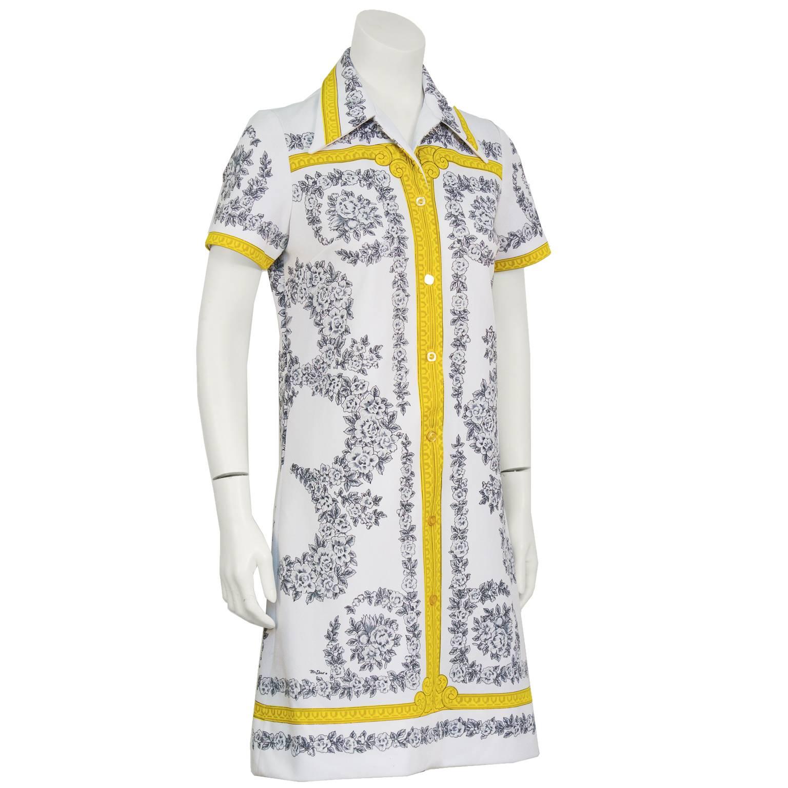 Mr. Dino, well know dress and fabric designer, 1960's polyester printed shirt dress. The dress features a black and white allover floral print with gold detailing along the collar, down the front, and on the sleeves. The back pattern features a gold