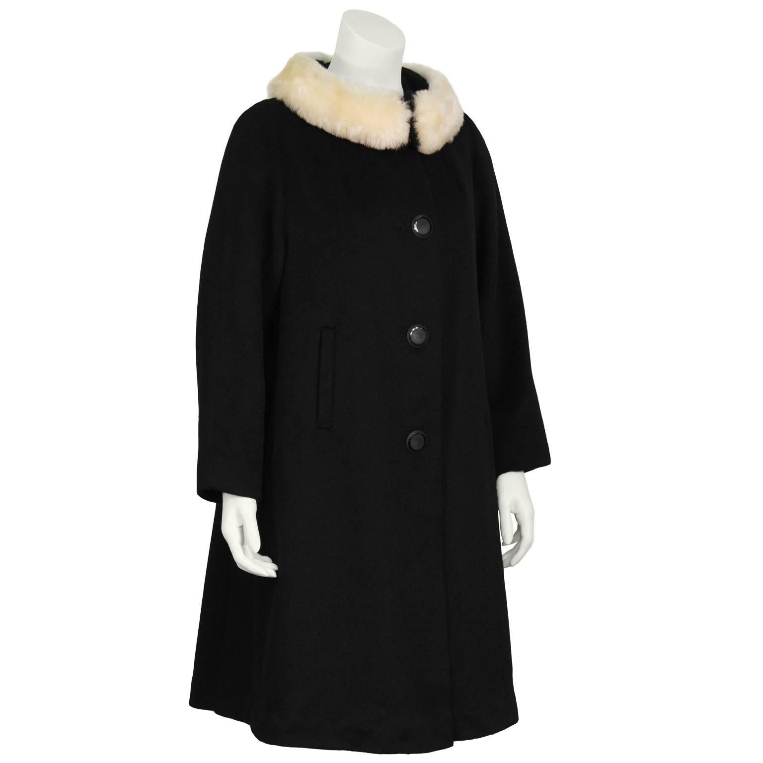 Lilli Ann 1960’s black wool swing coat with a cream faux fur detail at neck. The coat does up the front with large black circular buttons and the faux fur collar closes with large hook and eyes. Features two side slit pockets Still stitched close