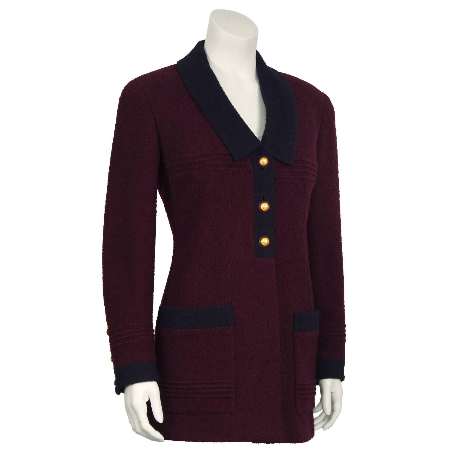 Chanel bordeaux and navy boucle car coat length jacket from the 1980's. The equestrian inspired coat is detailed with a navy Chelsea style collar that finishes with a placket front with three purple and gold circular Chanel buttons finished with two
