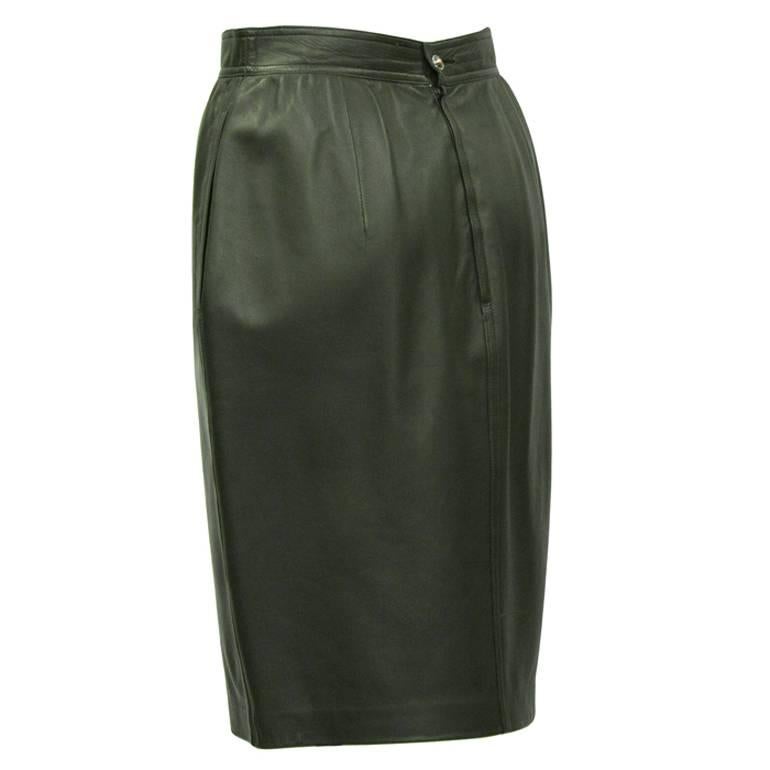 Emanuel Ungaro forest green leather pencil skirt from the 1980's. The buttery soft skirt features a banded waist, two side slit pockets and zips up the back. Features a silver logo button closure on the back. Fits like a US 2. Lined in a matching