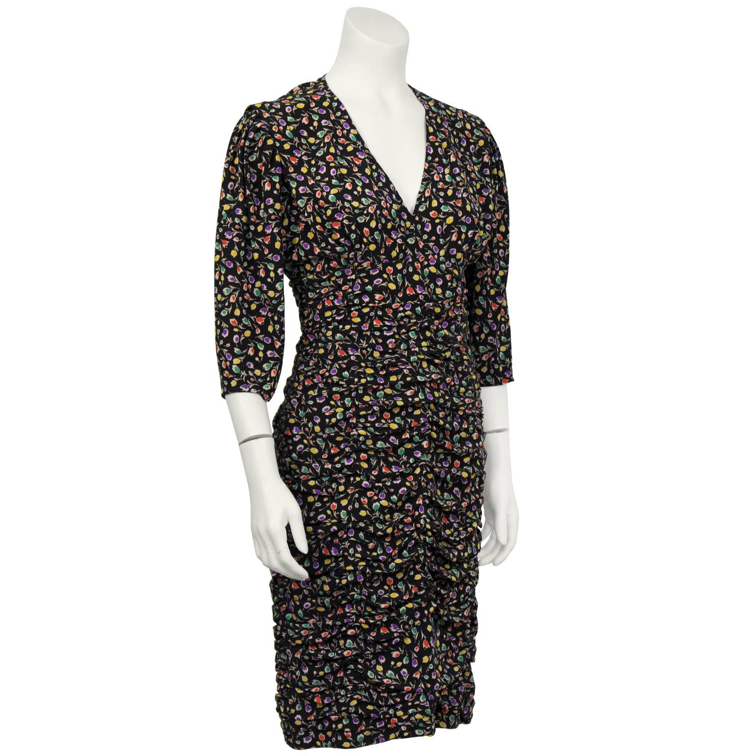 Iconic Ungaro black floral cocktail dress from the 1980's. The dress has a v-neckline and puffed ¾ sleeves finished with a black faceted button detail on the cuff. Typical Ungaro pick-up style ruching from the bust down to the hem. Zips up the back.