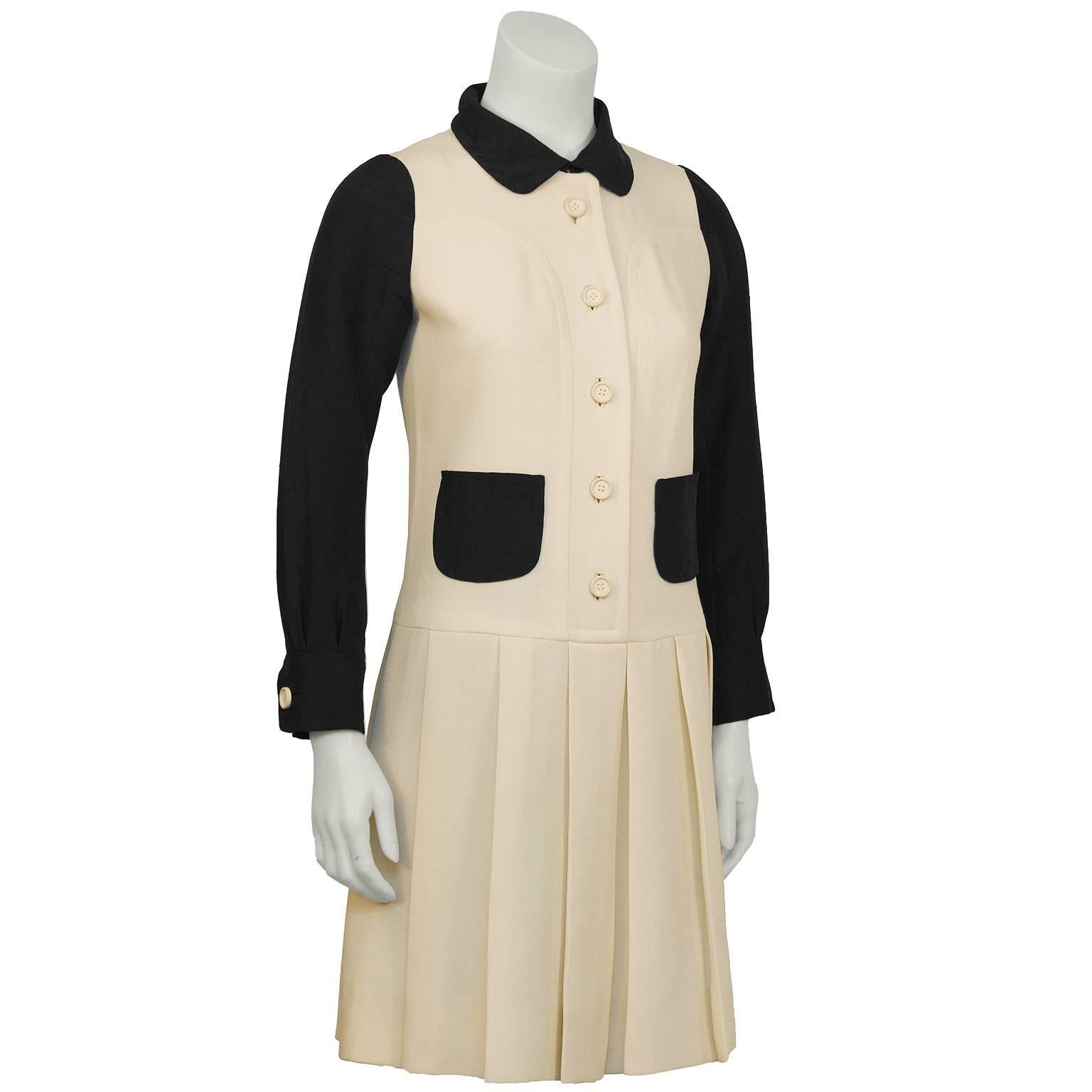 Ungaro Parallele black and cream drop-waist dress from the 1960's. The Courrèges inspired piece features black silk peter pan collar, sleeves, and front patch pockets as well as a half belt in the back. The dress buttons down the front with cream,