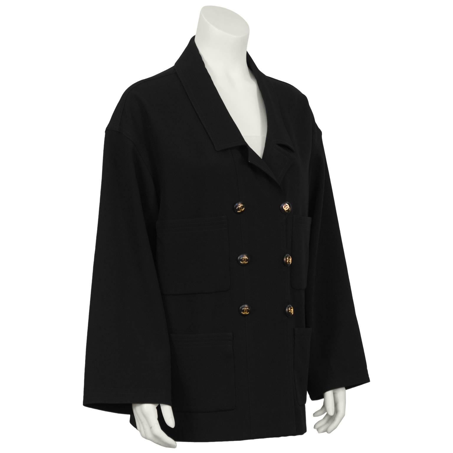 Late 1980's Chanel black wool-crepe deconstructed blazer. Features a notched lapel, double breasted with black and gold CC logo buttons, four front patch pockets. Overall relaxed fit and loose fitting sleeves. Excellent condition. Fits like a US 4-6
