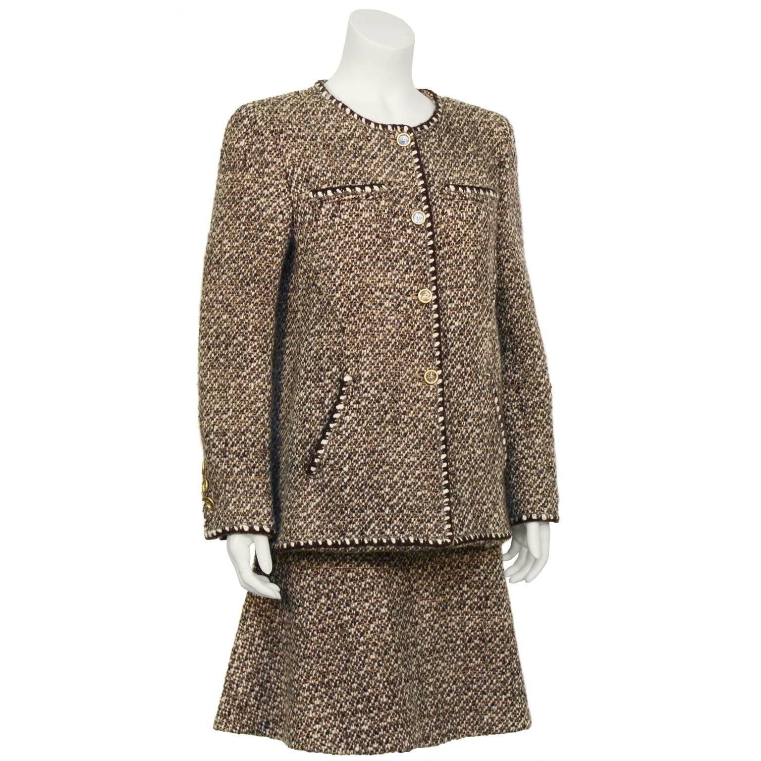 Chanel brown and white boucle skirt suit from the Fall 2001 collection. The slight a-line jacket has straight patch pockets on the bust, diagonal slit pockets at the hips and unique fabric filled plexi and gold tone buttons. The matching skirt
