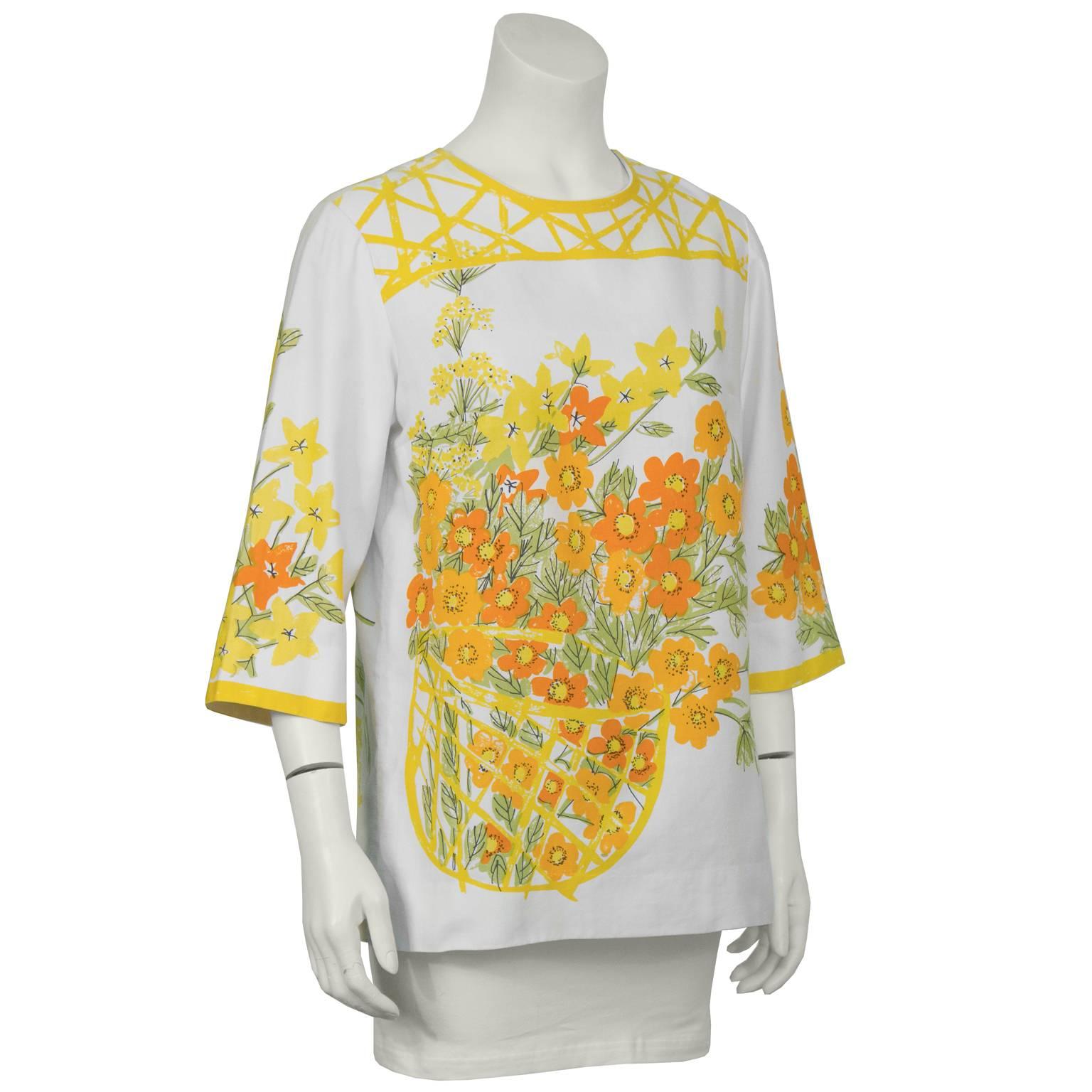 Vera cotton 3/4 length sleeve blouse from the 1960s. The blouse features a typical summery water color floral print of orange and yellow flowers with green leaves in a basket on the front and on the back, and on the sleeves. Darts at the bust, zips