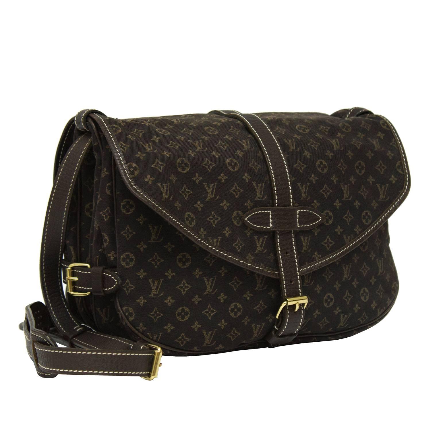 Louis Vuitton dark brown cotton monogram Saumer 30 with dark brown leather trim. The double-sided saddle bag has a top flap entry on each side with a buckle closure. The adjustable crossbody shoulder strap features a shoulder pad with a plastic