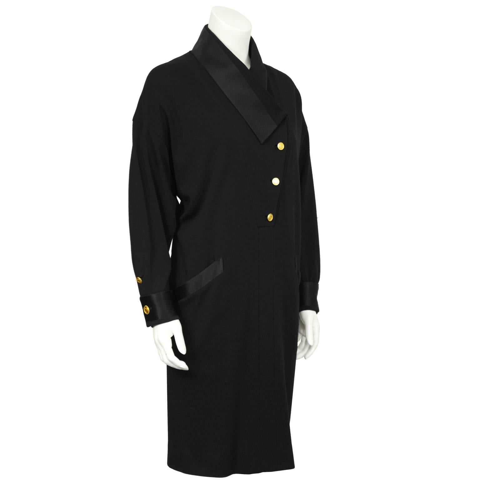 Unique style dress features an asymmetrical collar finished with gold buttons stamped with “Coco Chanel France” surrounding Coco’s profile. The dress features diagonal pockets on the front trimmed in black satin and the cuffs have matching gold