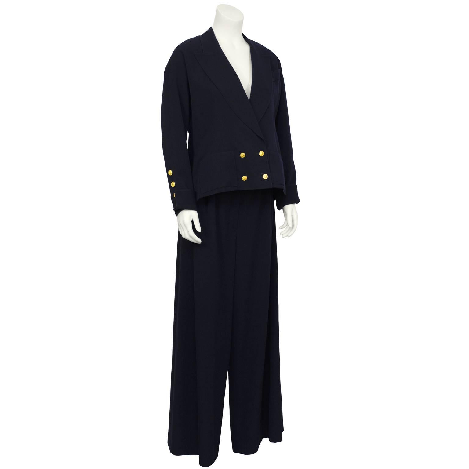 Chanel 1980's navy wool gabardine belted pantsuit. The short box-shaped double-breasted jacket is detailed with gold CC buttons on the front and at the turned cuffs. Features a notched lapel with one diagonal breast pocket and two front patch